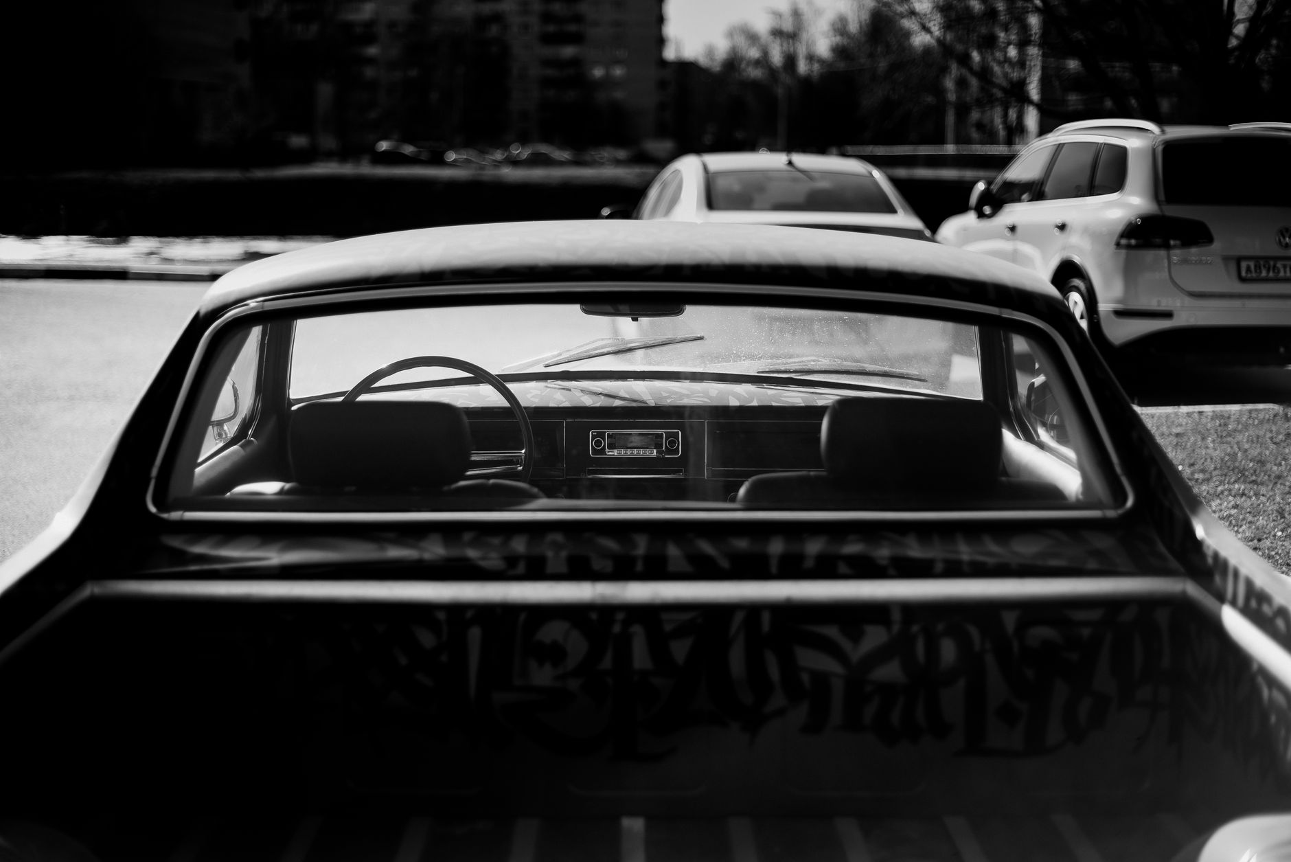 A classic pickup truck in a black and white urban parking lot setting.