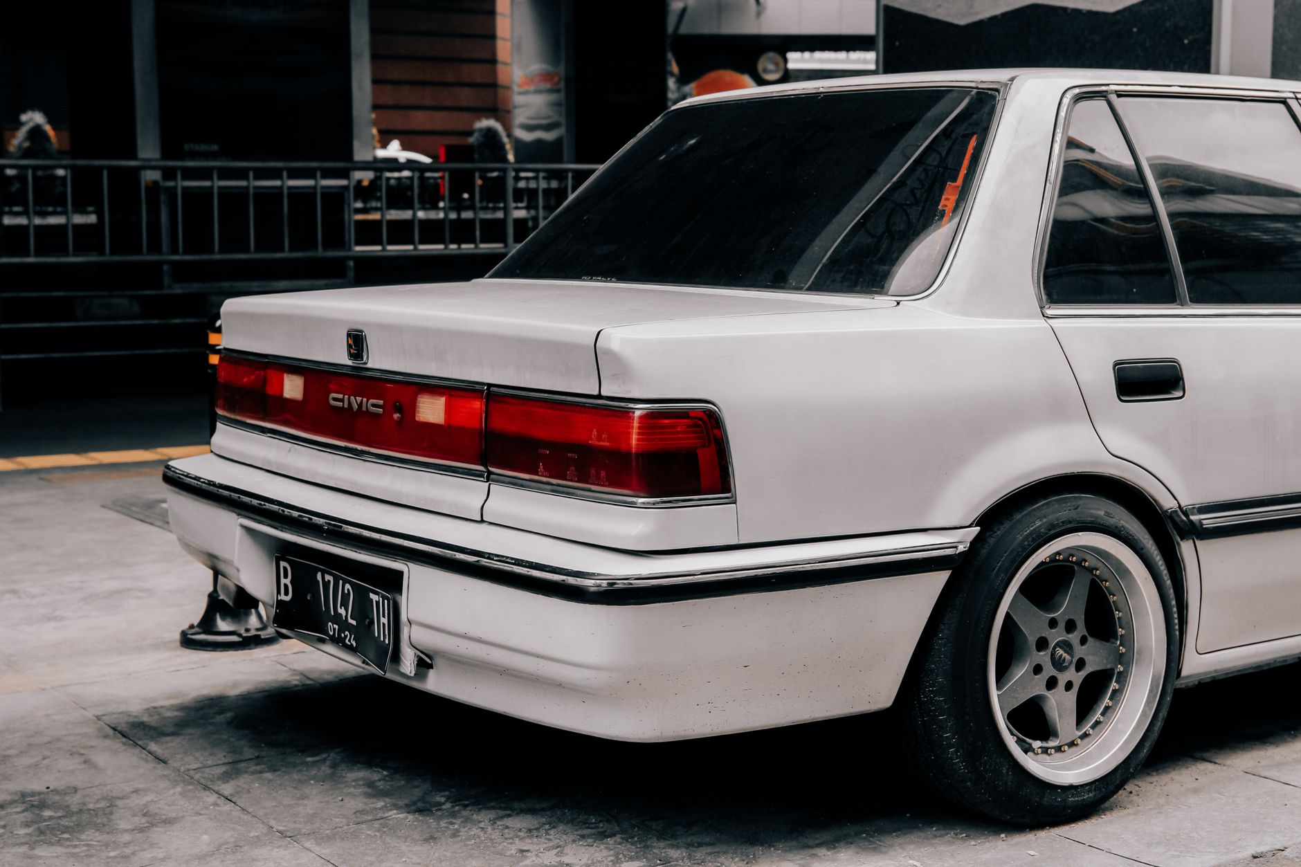 A vintage white car parked in an urban area in Indonesia, showcasing classic automotive design.