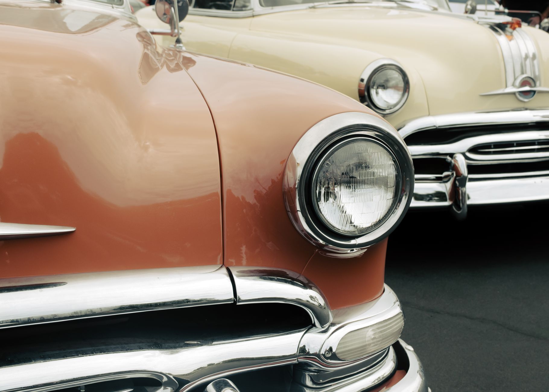 Close-up of vintage cars at an outdoor classic car show, showcasing chrome details.