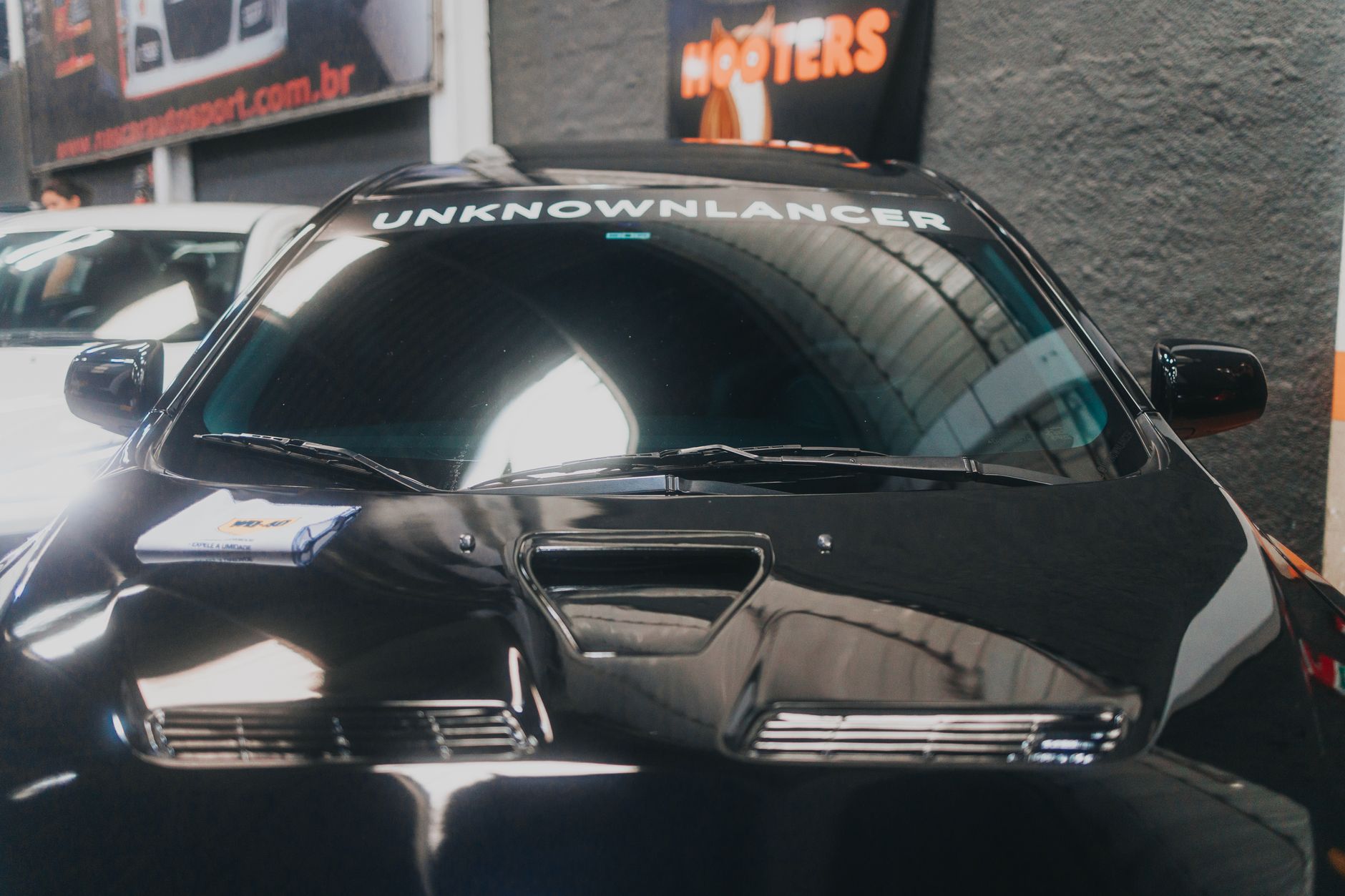 Front view of a sleek modified black car displayed in a showroom with distinctive branding.