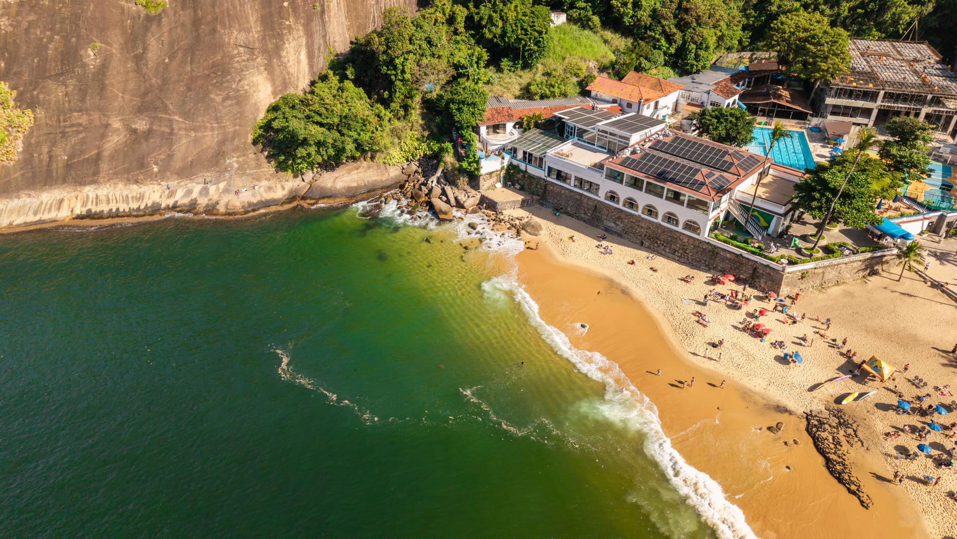 Sunny aerial shot of a vibrant Rio de Janeiro beach with golden sands and turquoise waters.