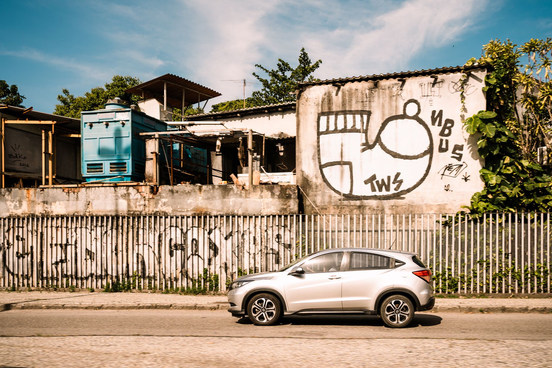 A car passes graffiti-covered buildings in sunny Rio de Janeiro, Brazil.