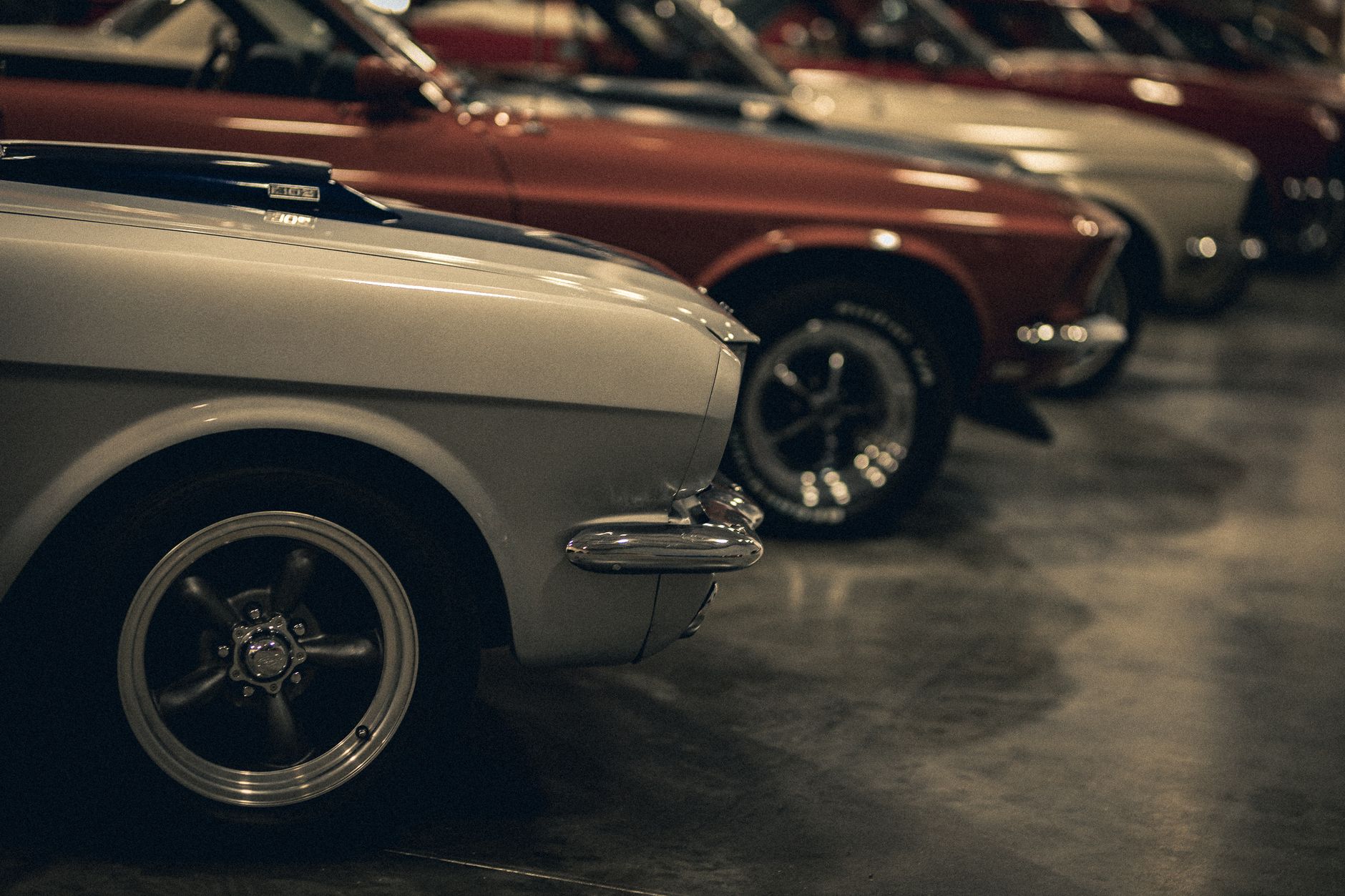 A close-up view of a row of classic vintage cars in a dimly lit garage showcasing elegance and retro design.