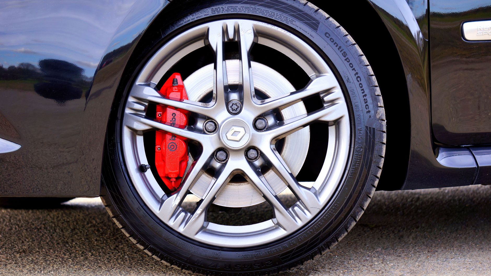 Detailed view of a Renault car wheel with a red brake caliper on display.