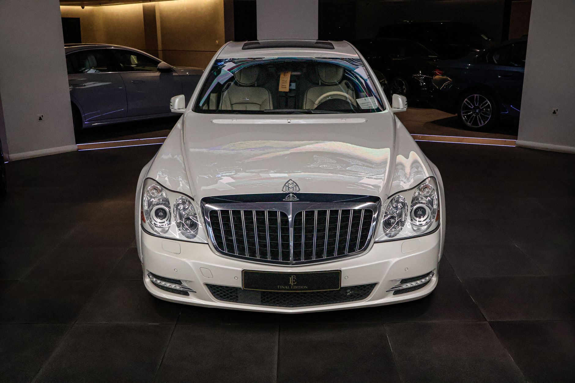 Front view of a luxury white car displayed in an elegant indoor showroom.