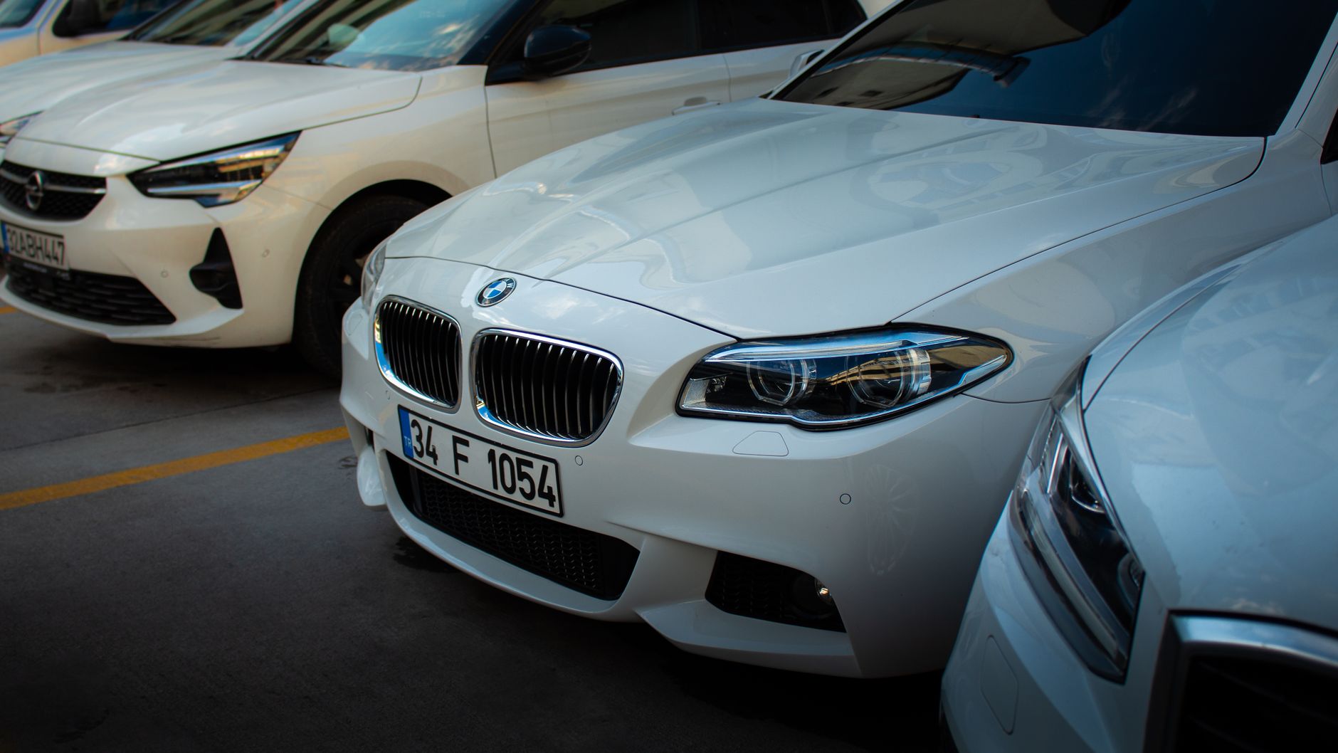 A sleek white BMW car parked in an urban setting alongside other vehicles.
