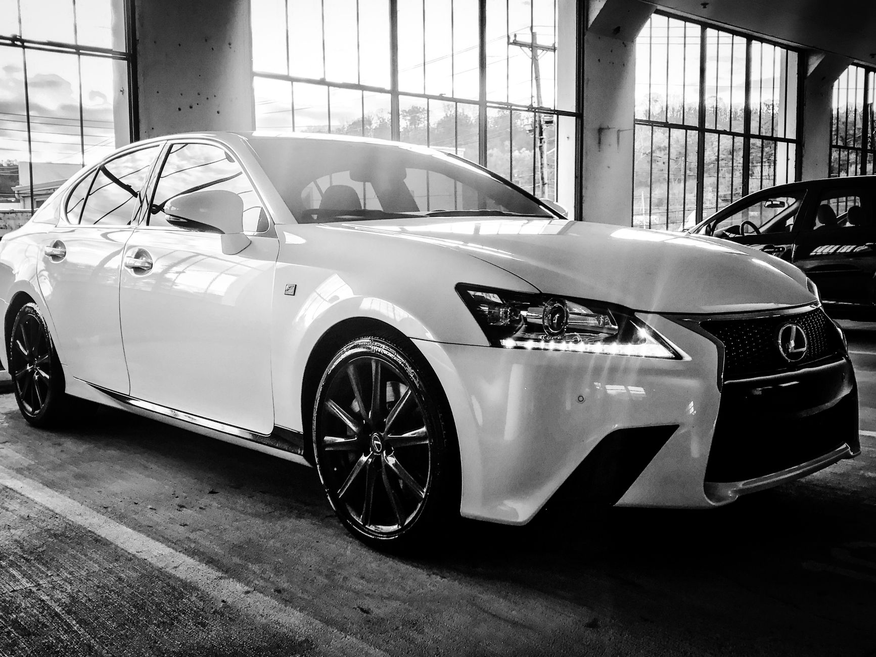 A stylish Lexus sedan showcased in a black and white indoor setting, highlighting its luxury design.