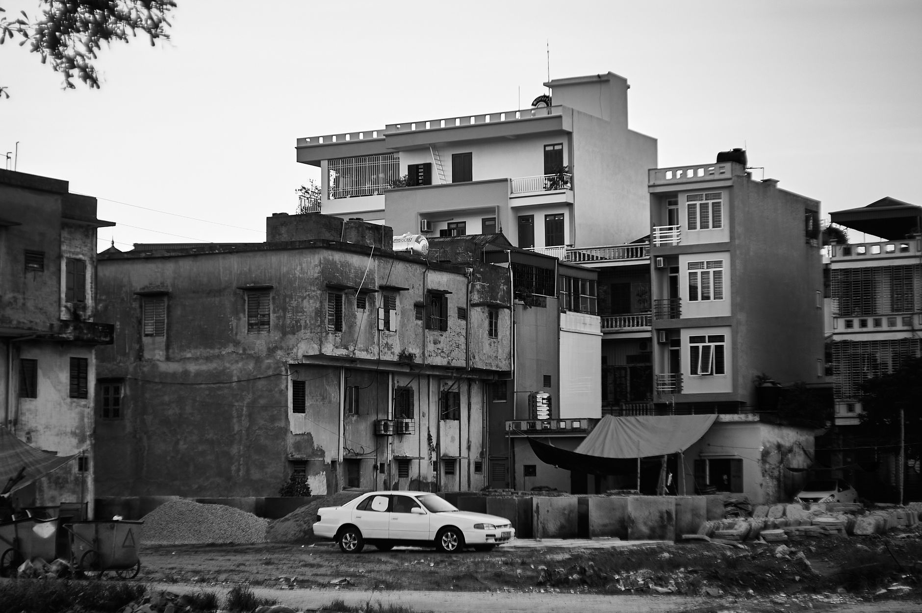Grayscale image of buildings and a car in Thái Bình, Vietnam, depicting urban life.