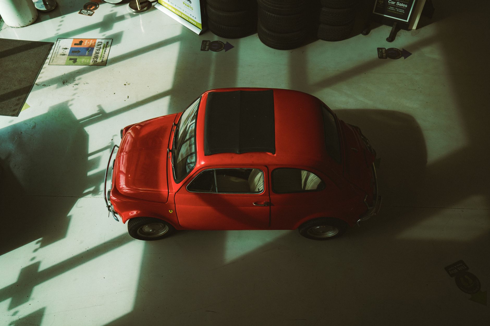 Aerial shot of a classic red Fiat car in indoor lighting, showcasing its vintage design in England.