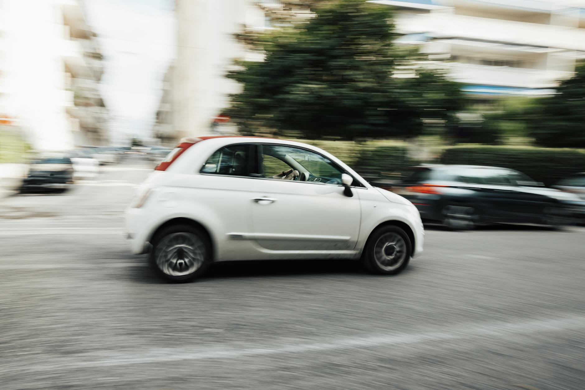White car speeding through city street with motion blur effect highlighting fast motion.