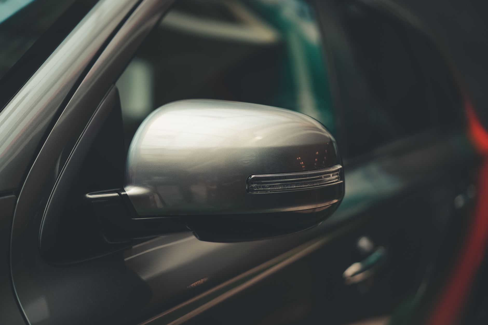 A detailed close-up of a car's chrome side mirror, showcasing modern design.