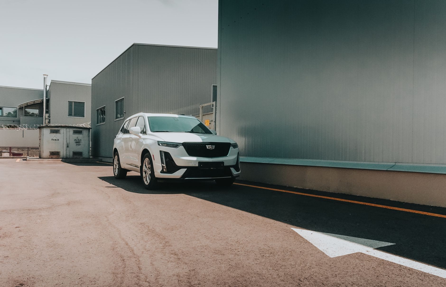 A white SUV parked outside an industrial building in daylight, showcasing its elegant design.