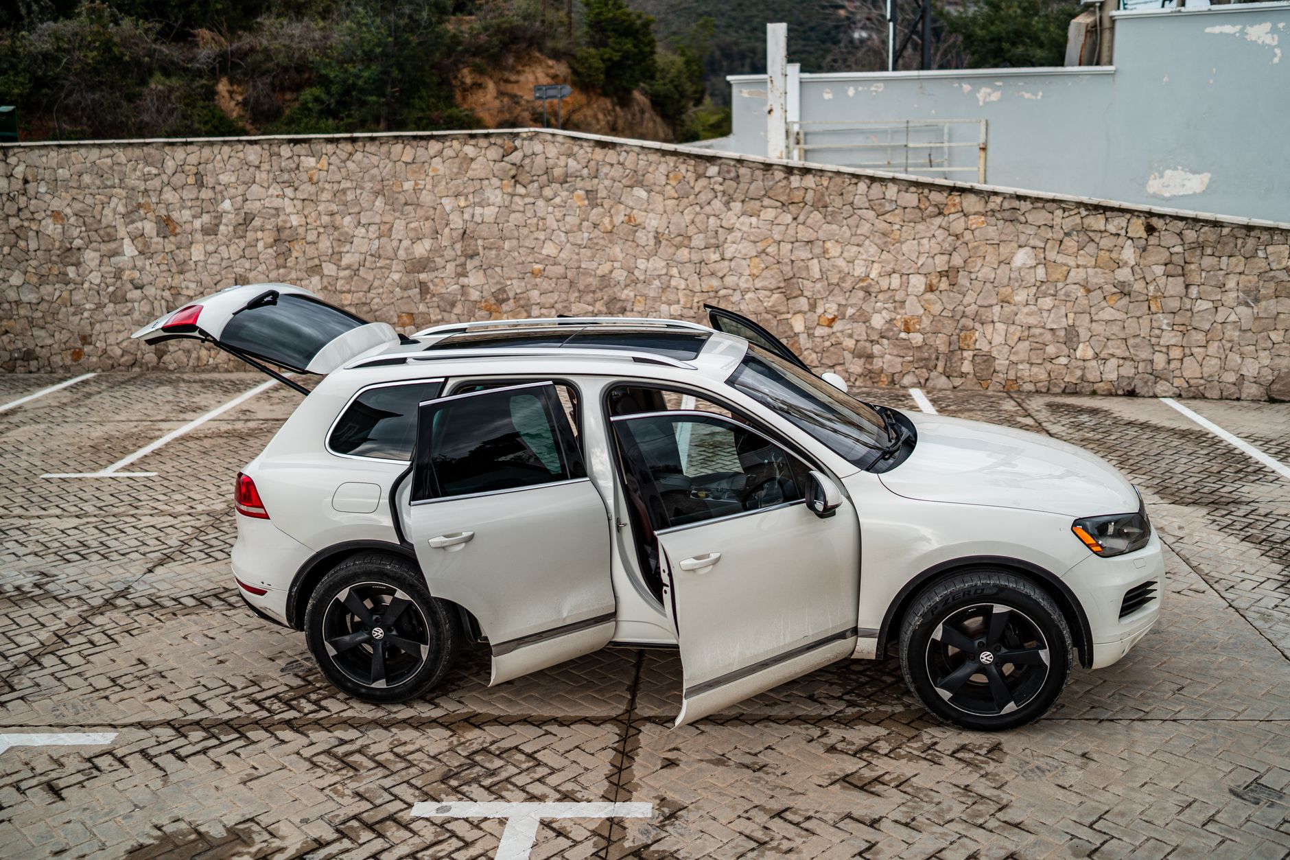 A white SUV with open doors parked in an outdoor parking lot, showcasing a modern design.