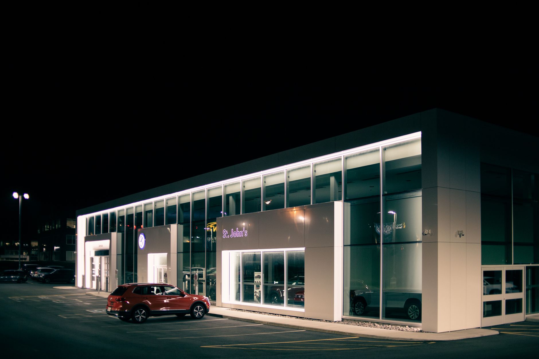 Off road car parked near entrance of shop with luminous lights at dark night
