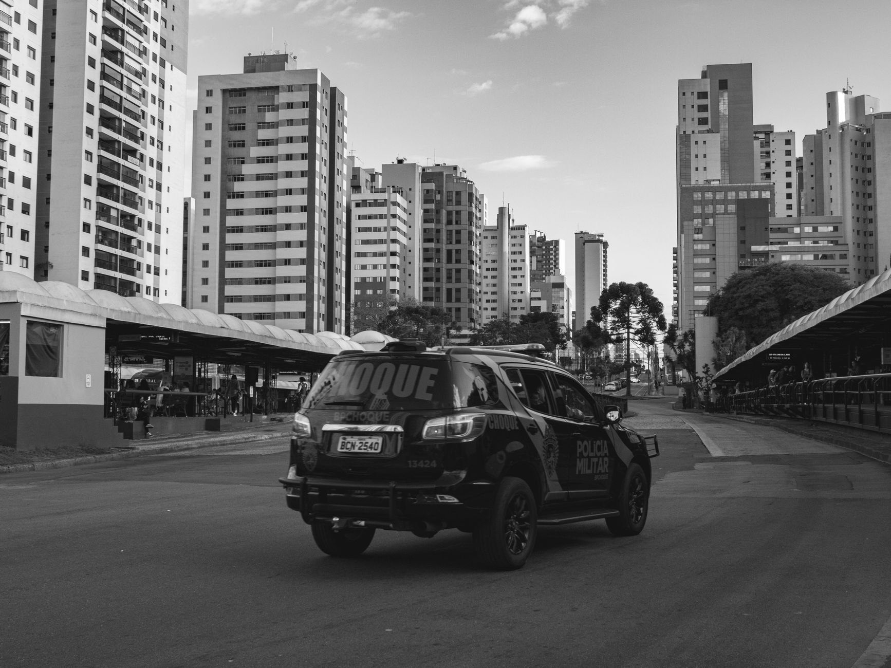 A police SUV patrols a modern city street with skyscrapers.