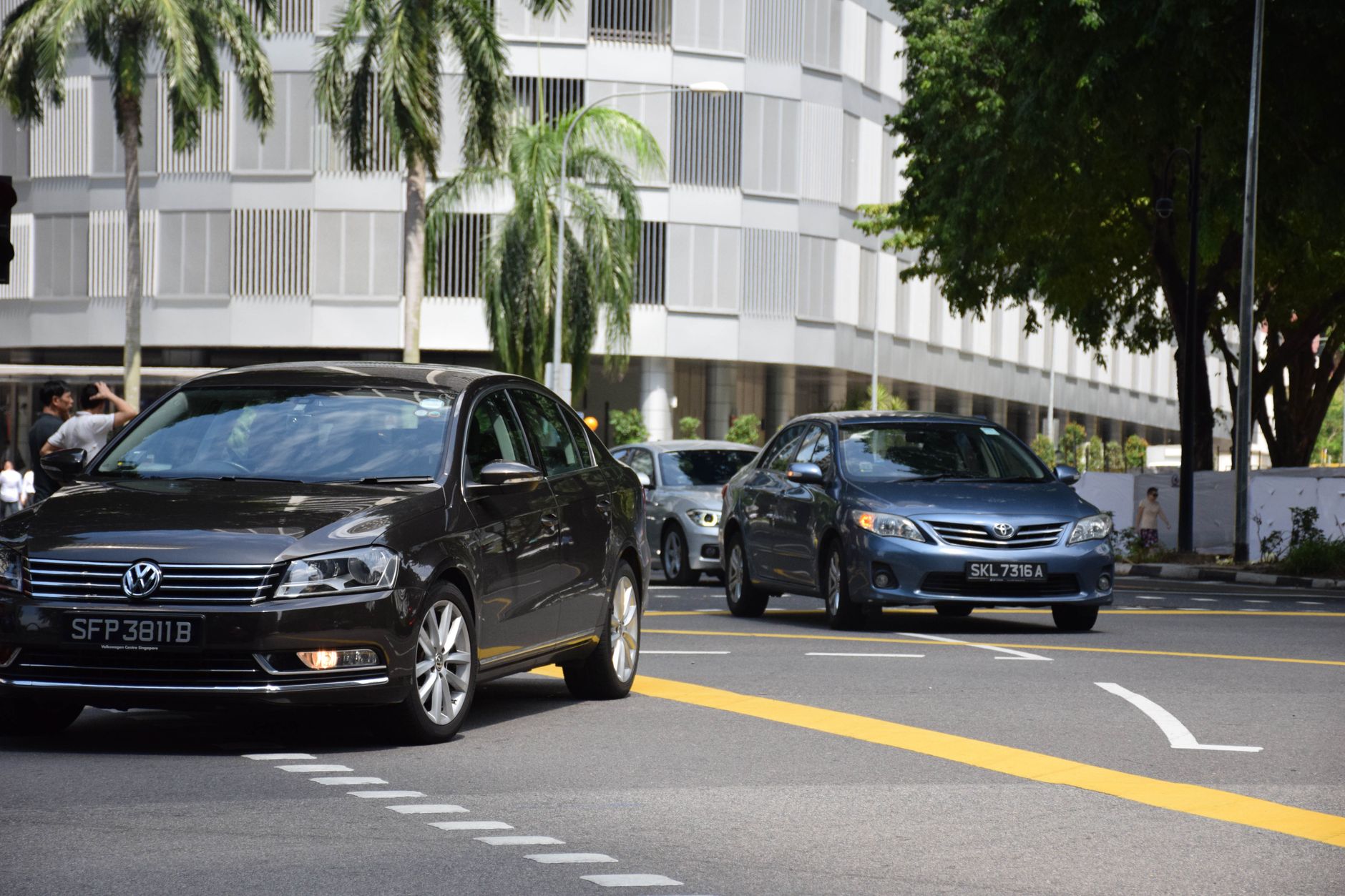 Busy city street in Singapore featuring several cars with modern building facade.