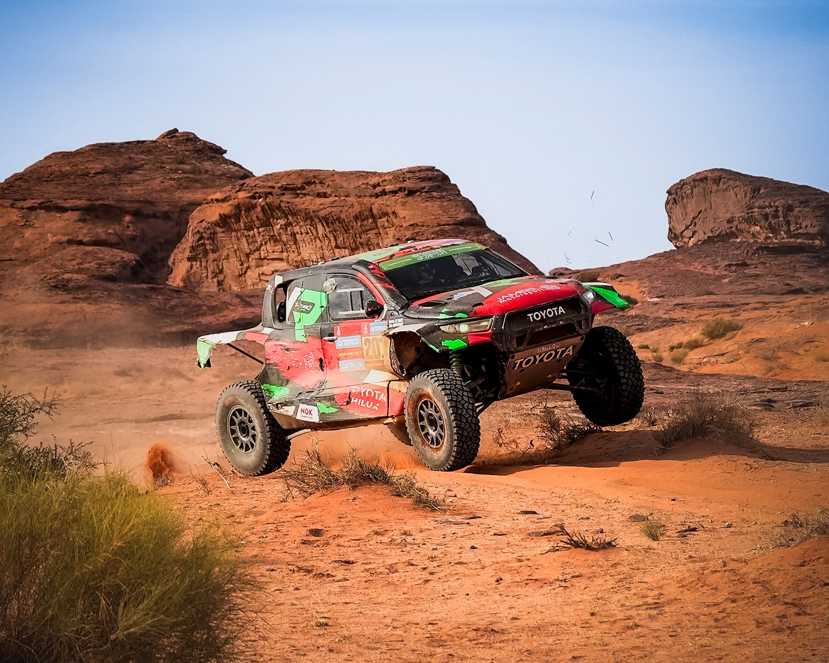 Dynamic off-road rally car in action on rugged desert landscape.