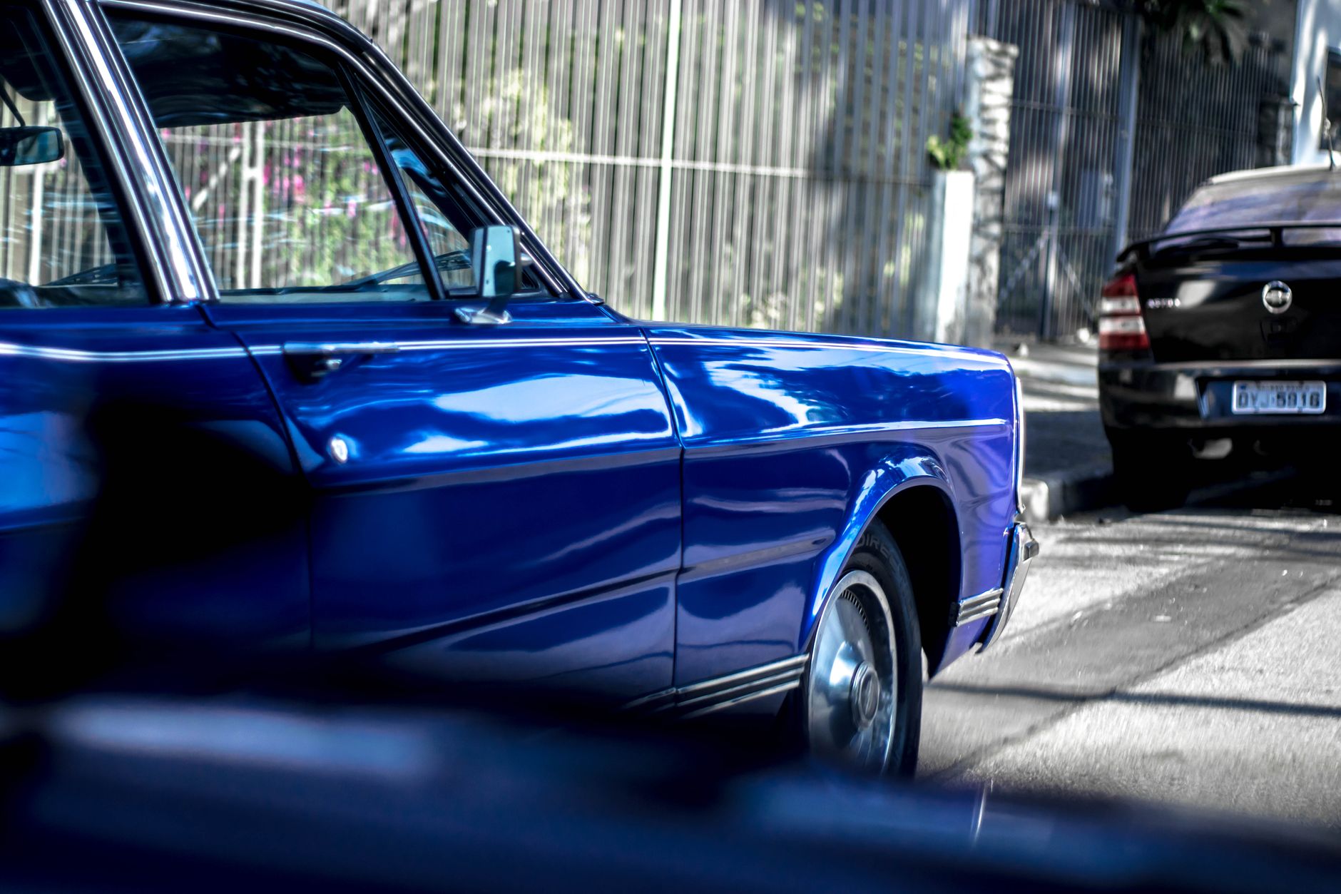Shiny vintage car of blue color parked on sunny roadside on narrow street