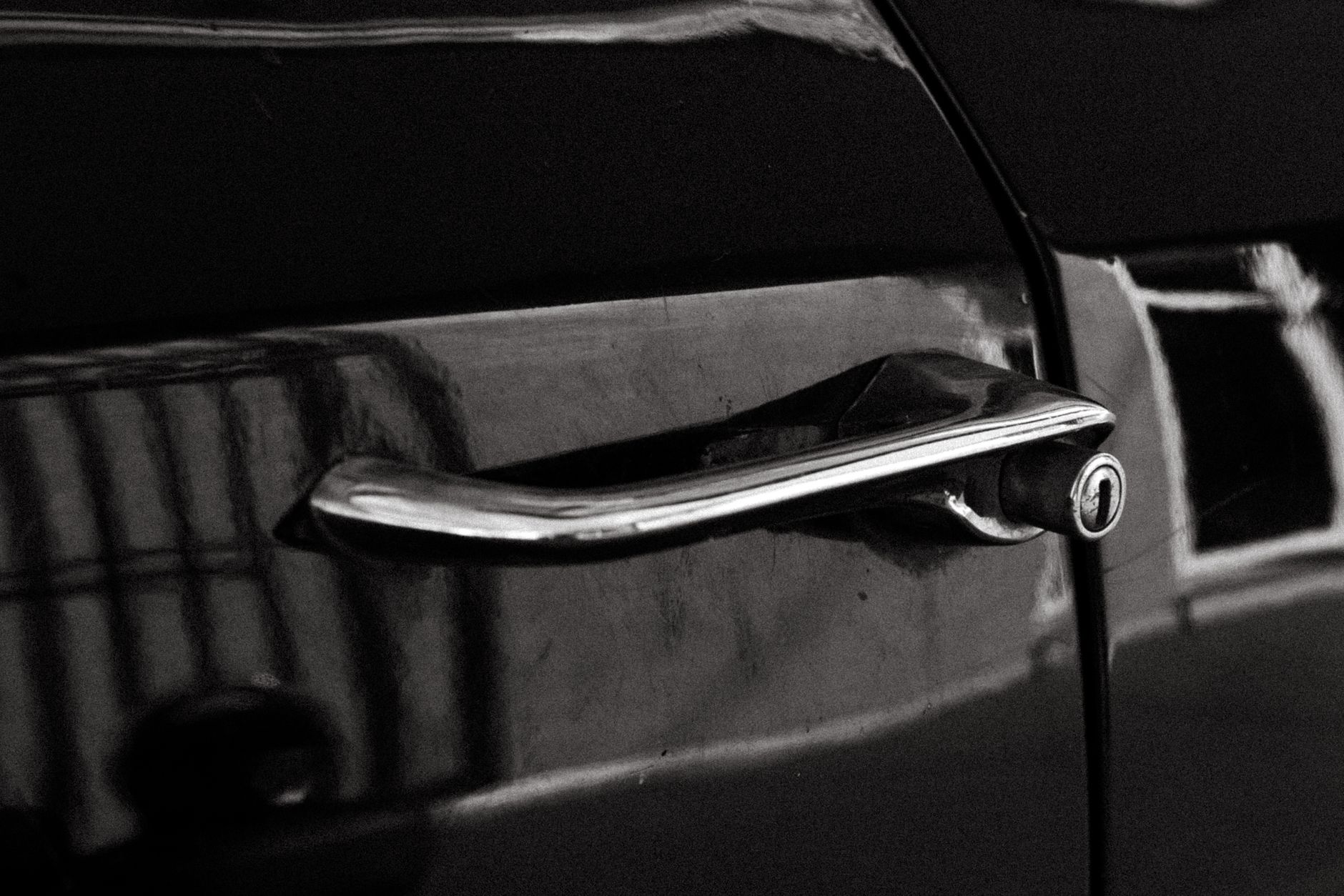 Close-up of a vintage car door handle in a black and white photograph, showcasing retro design.