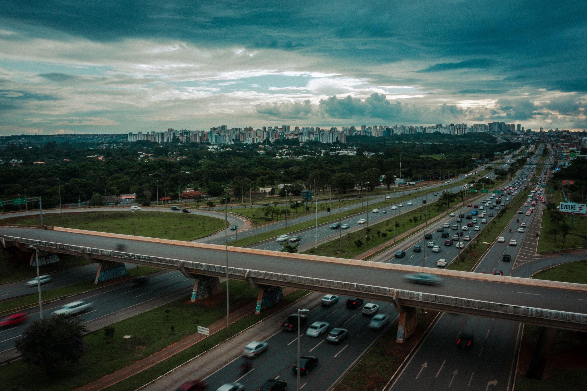 Aerial cityscape of Brasília with busy traffic on highway and cloudy sky.