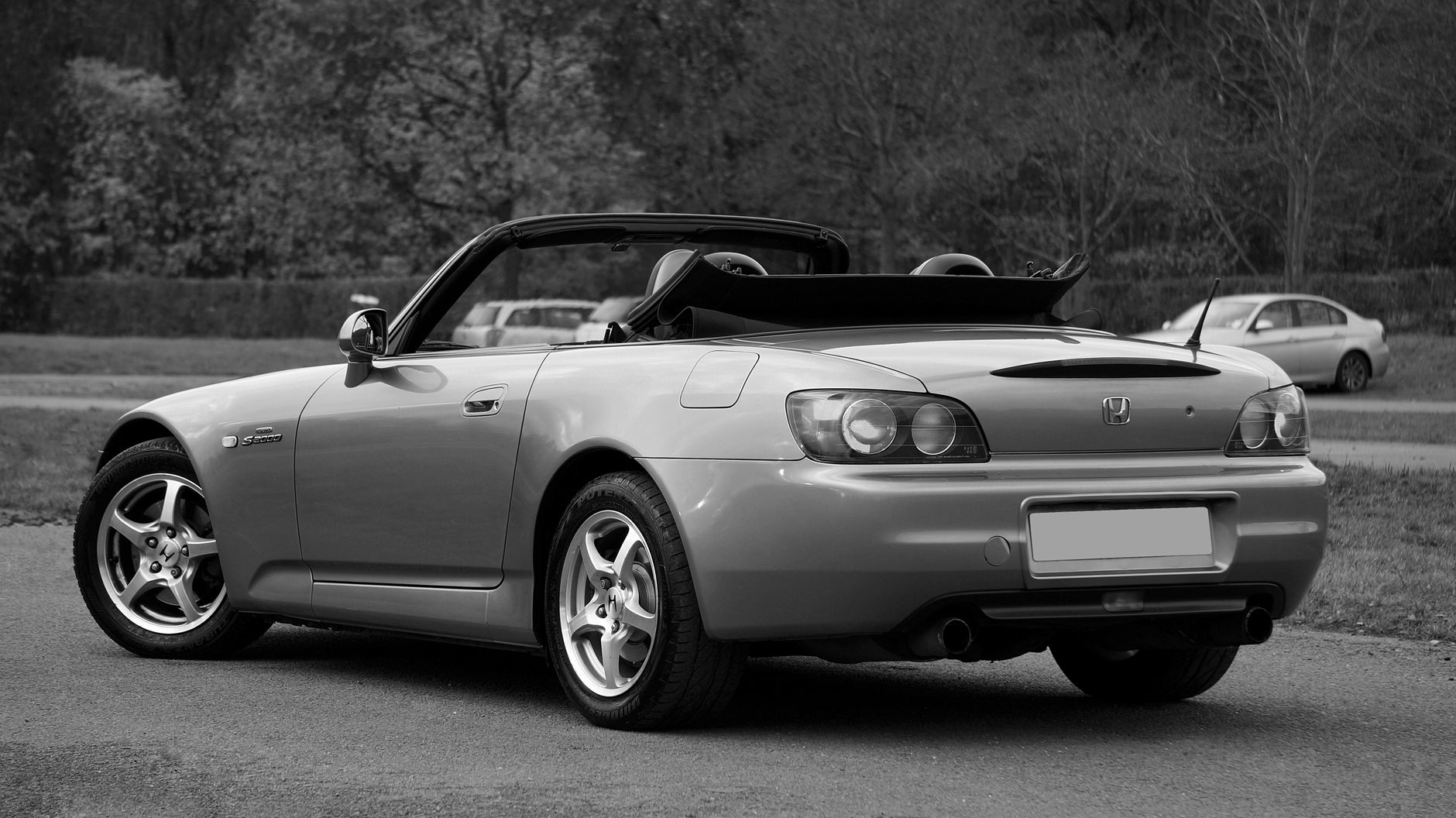 Black-and-white image of a convertible car parked outdoors, showcasing luxury design.