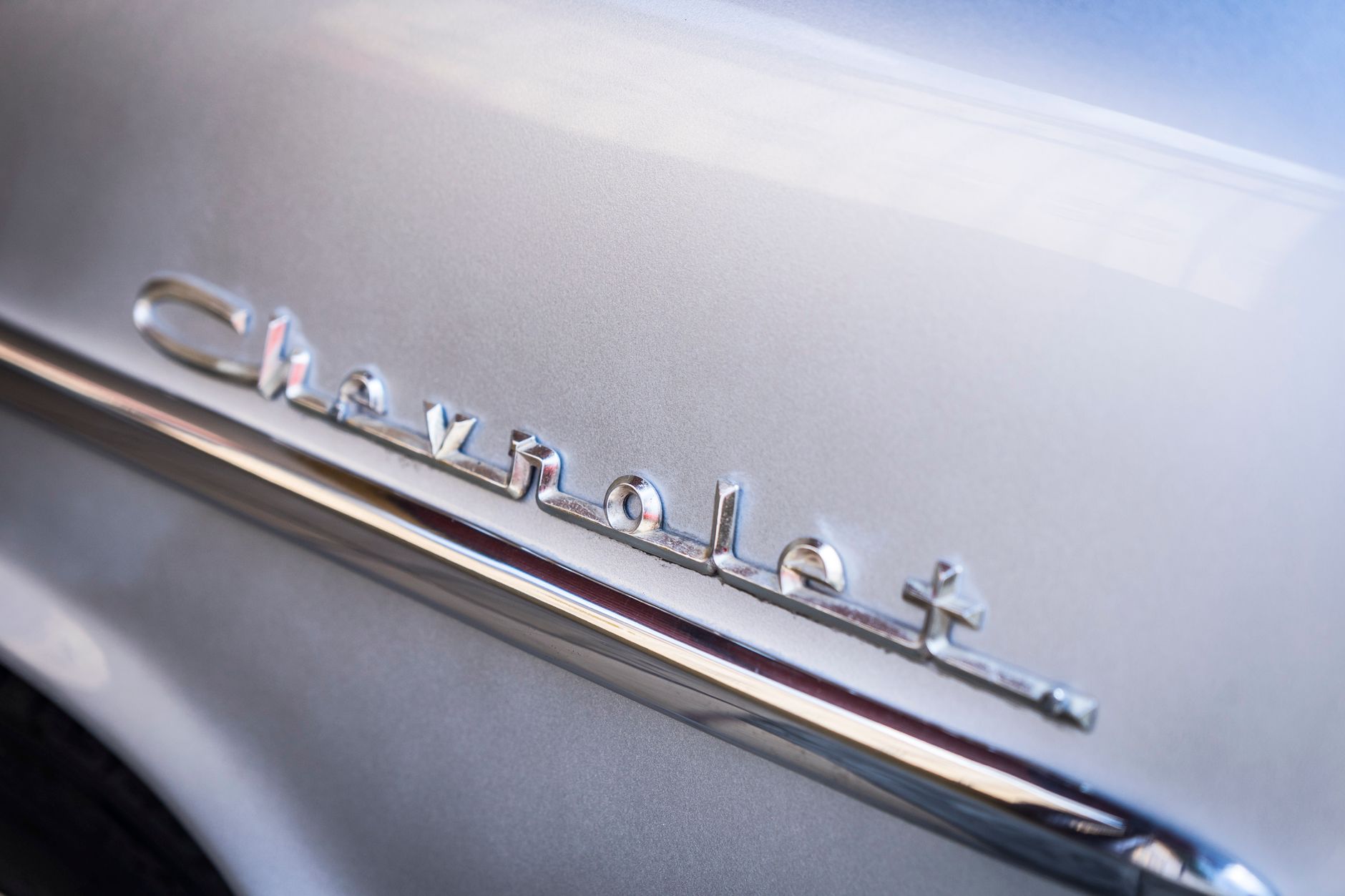 Detailed shot of a vintage Chevrolet emblem in chrome reflecting light. Ideal for automobile enthusiasts.