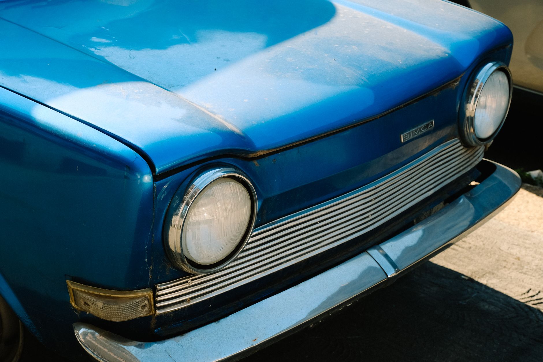 Detailed view of the front of a classic blue Simca car, showcasing headlights and bumper.