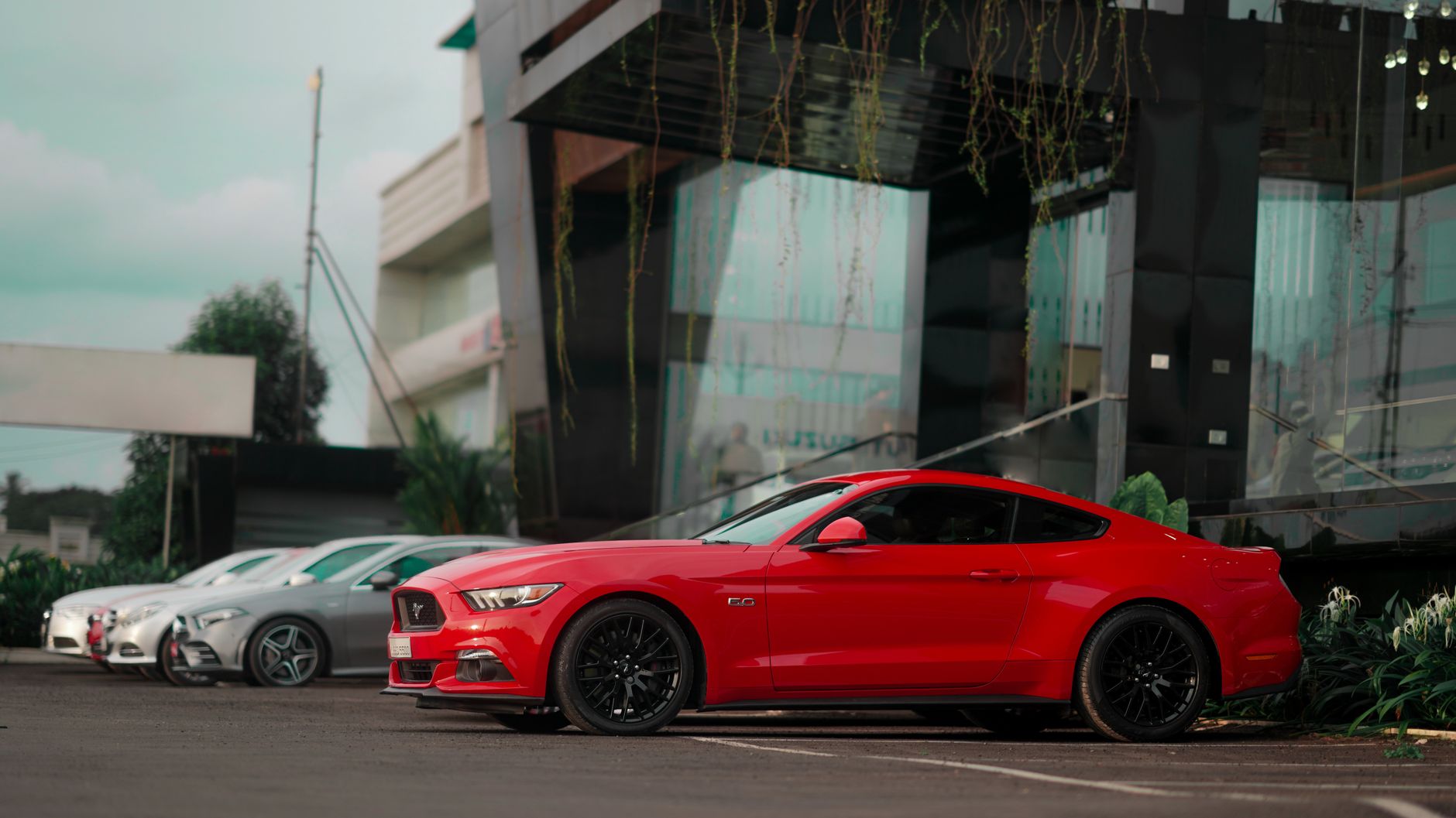 Red sports car parked in a city reflecting urban architecture.