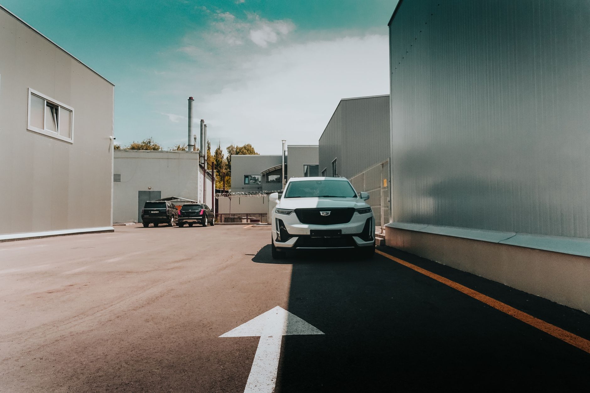 A white SUV parked outdoors in an industrial area with buildings in Almaty, Kazakhstan.