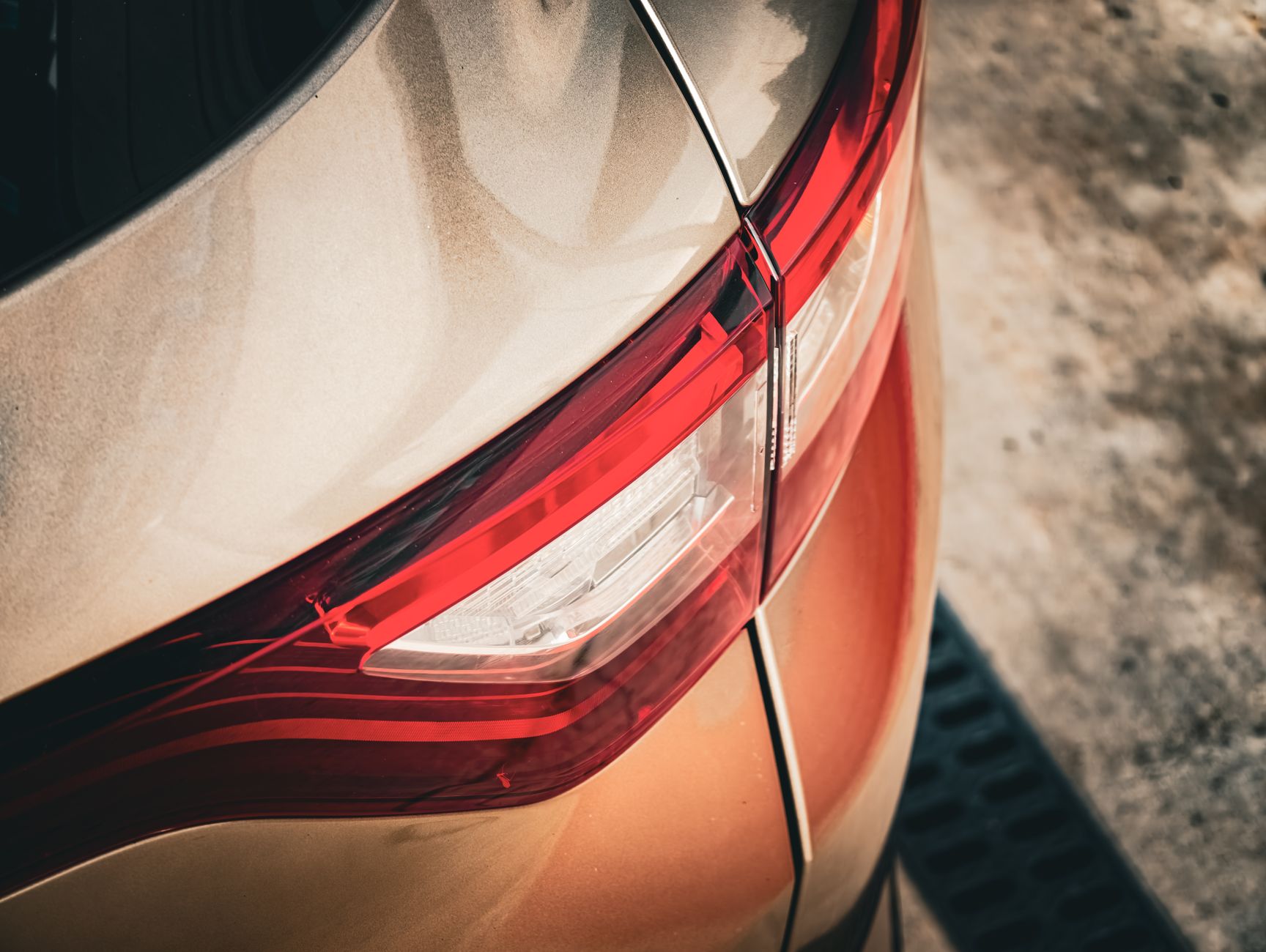 Detailed view of a modern car's tail light showing sleek red and gold design.