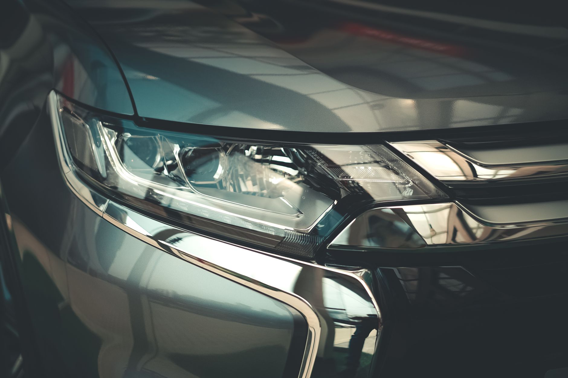 Detailed close-up of a modern car headlight with sleek chrome finish, emphasizing design and technology.