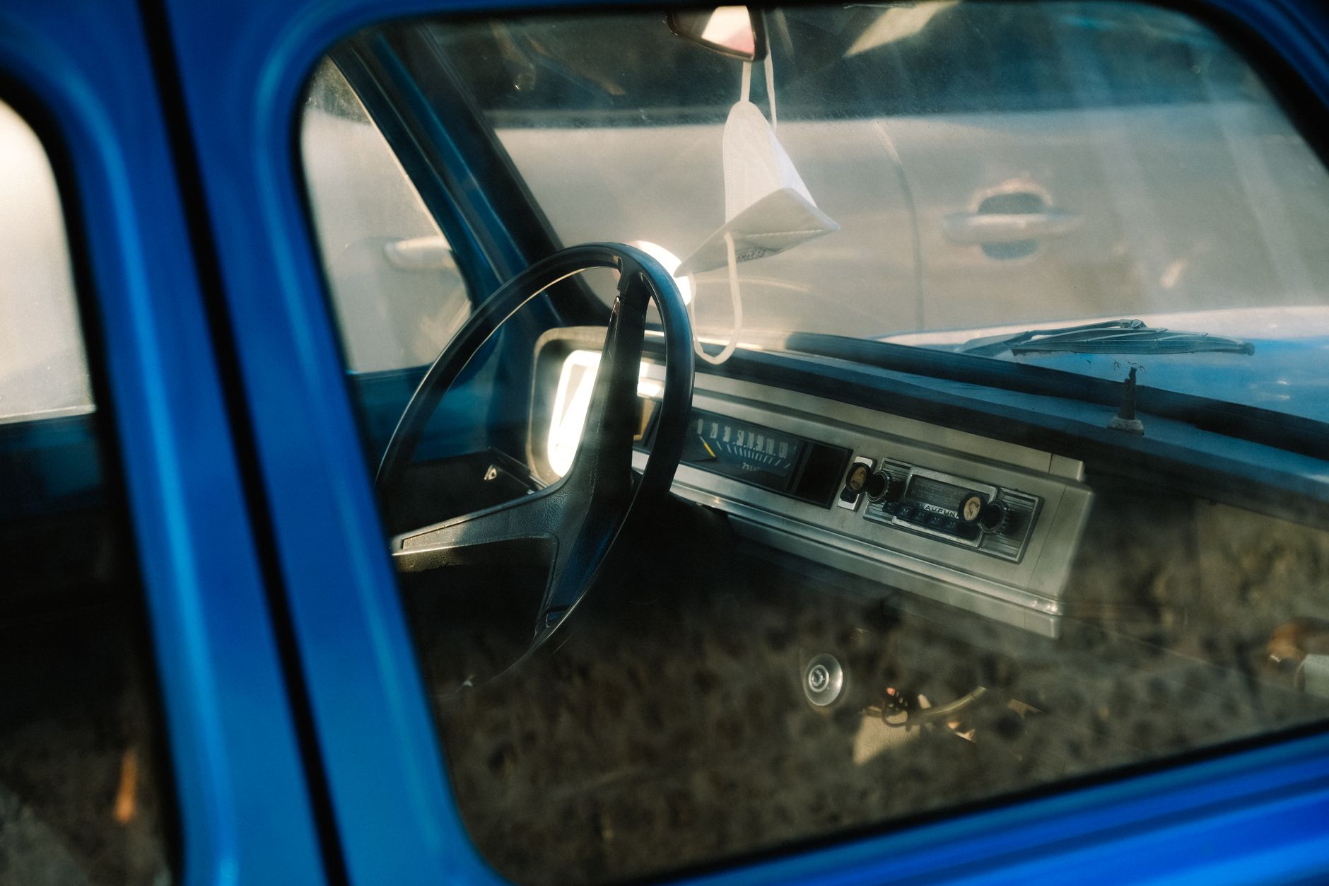Explore the classic vintage interior of a blue car, featuring dashboard details and steering wheel.