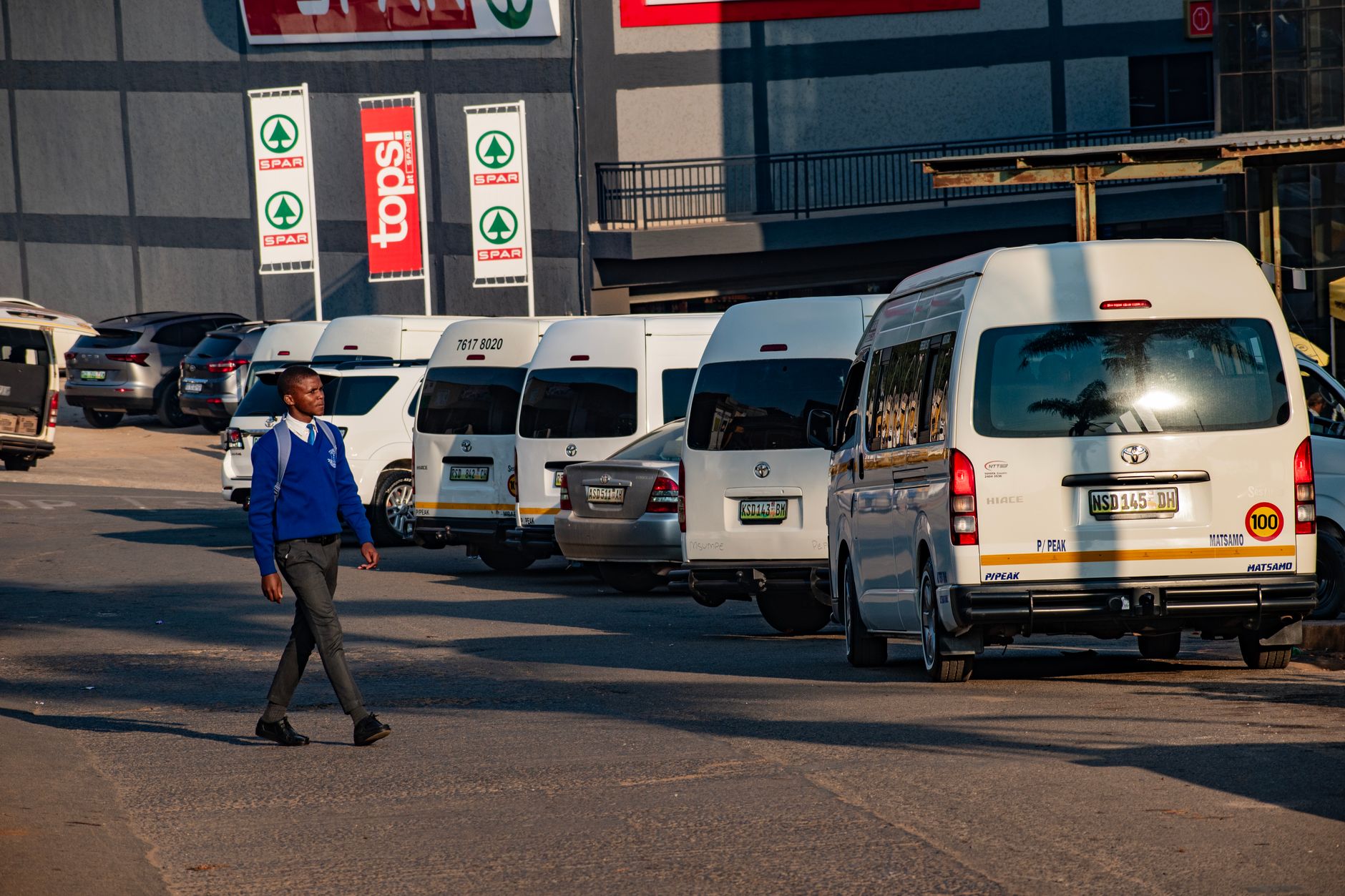 A man walks by a row of parked minibuses in Manzini, Eswatini.