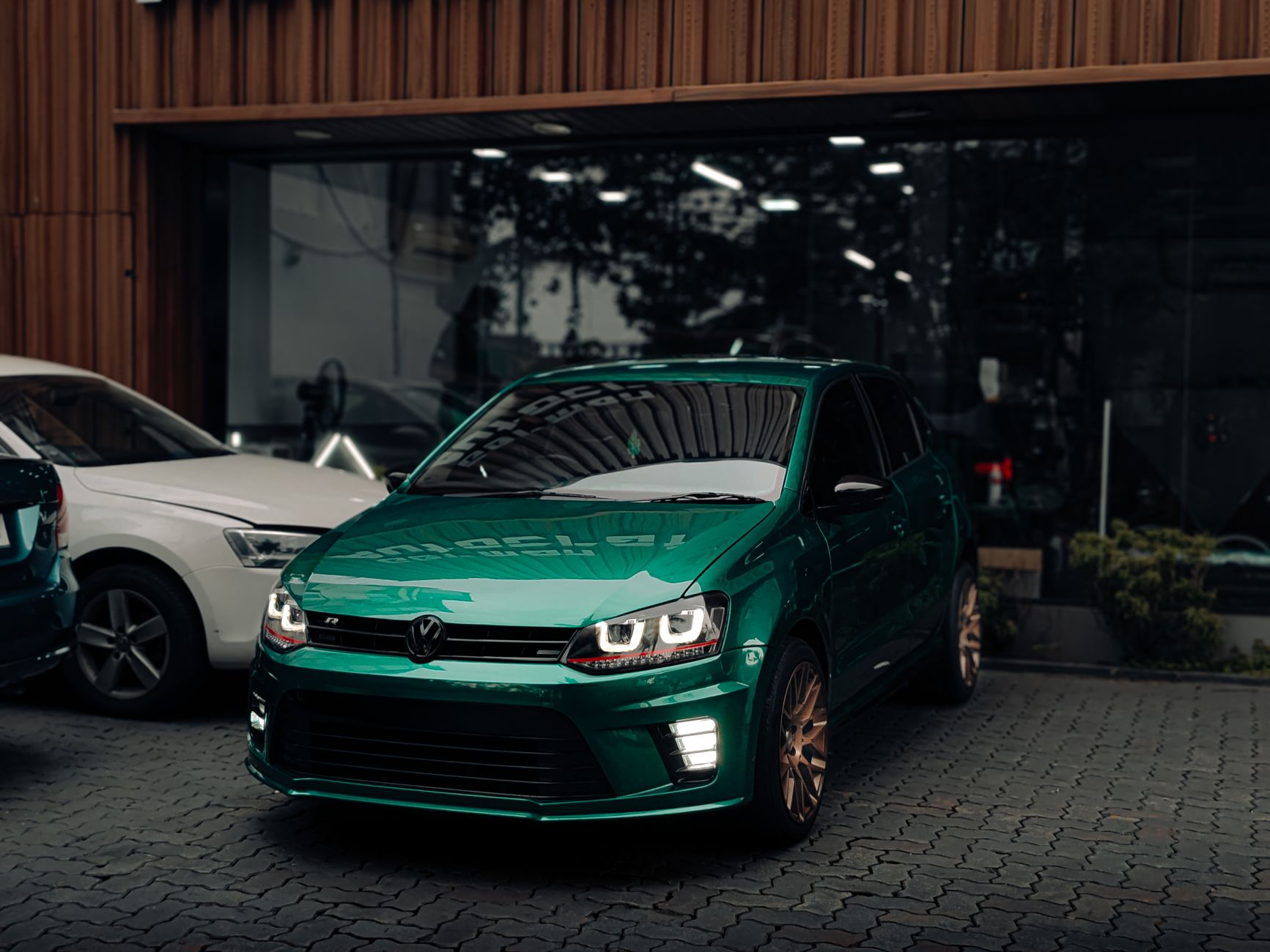A sleek green Volkswagen parked outside an auto dealership in Kochi, India.