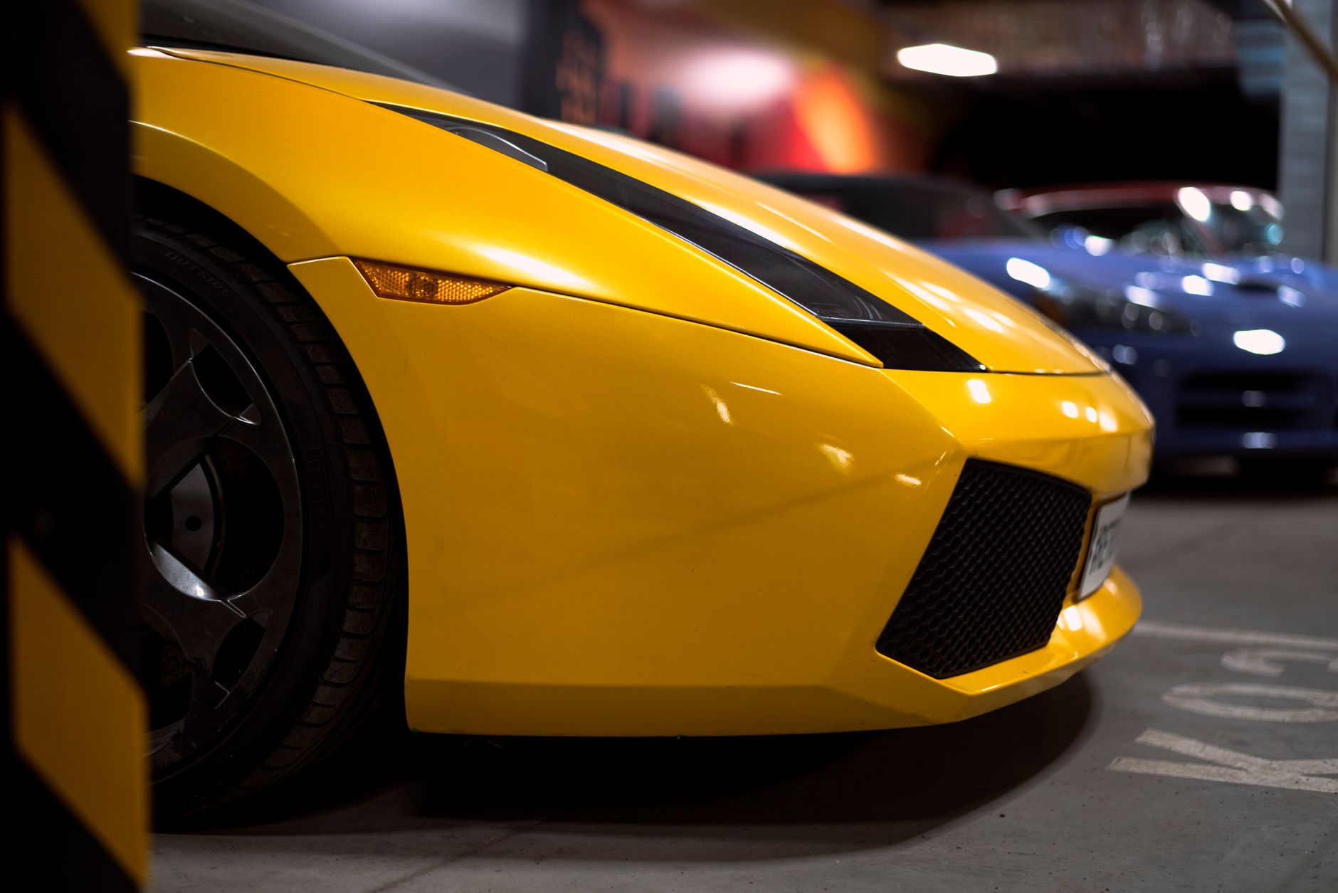 Close-up of a vibrant yellow Lamborghini Gallardo in a showroom, highlighting its sleek design.