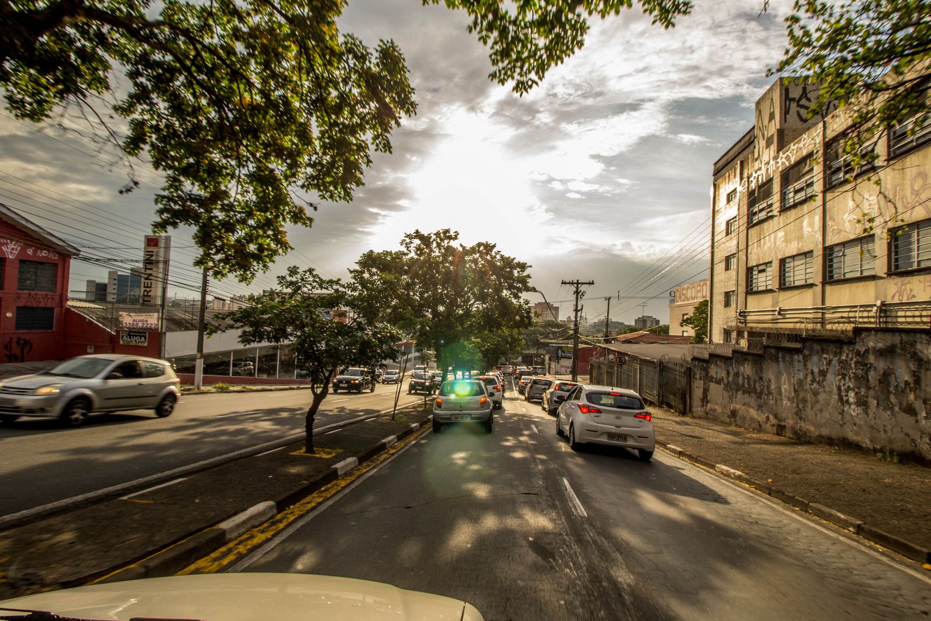 Traffic on a sunny urban street with cars and city buildings in view.