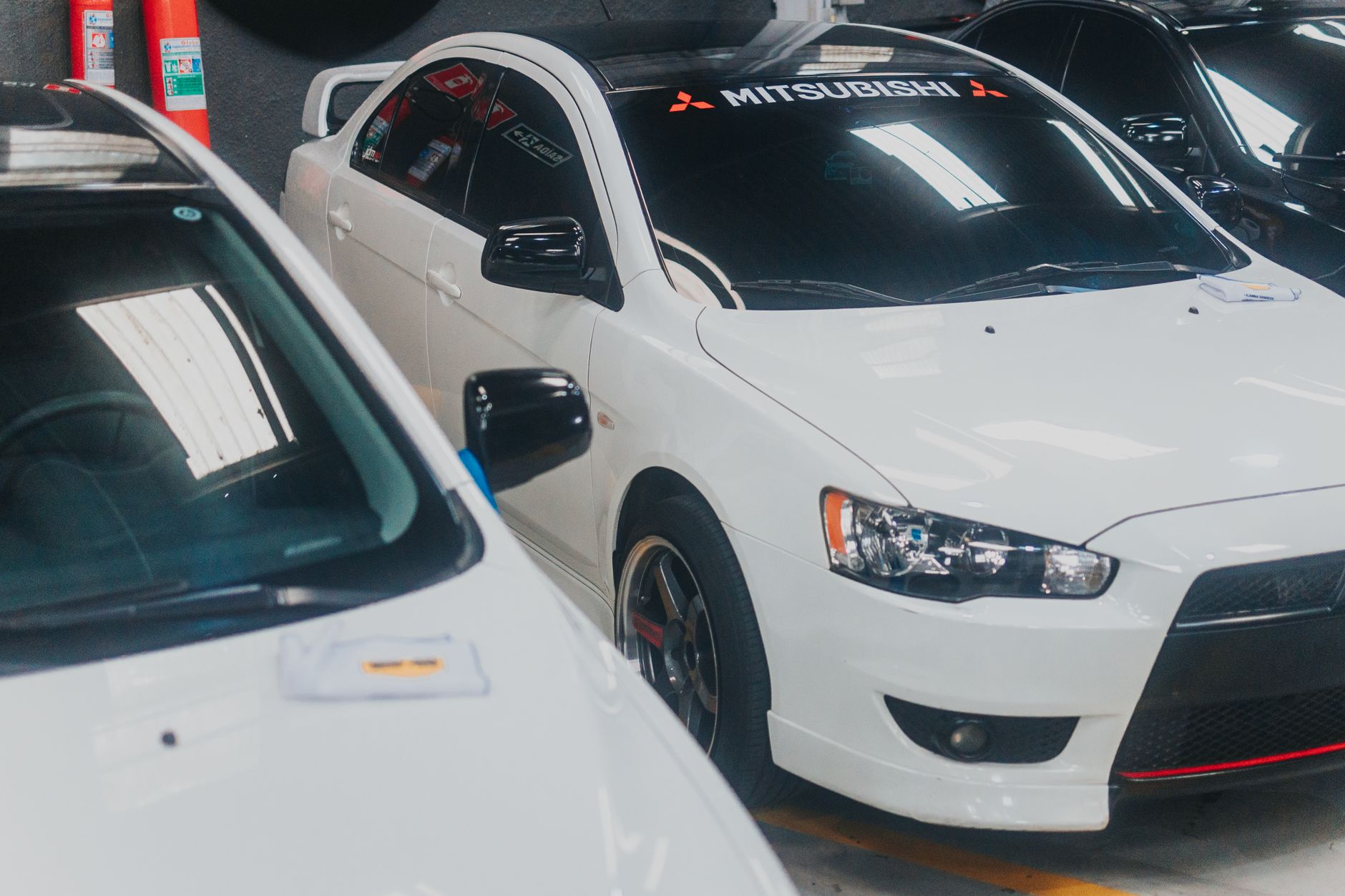 Close-up of a white Mitsubishi Lancer with decals in a garage setting.