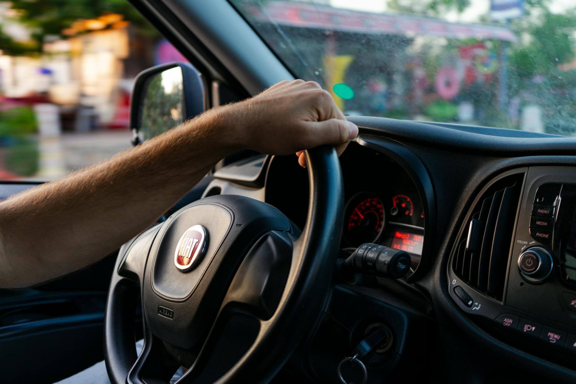 Close-up of a hand on a Fiat steering wheel while driving in Fethiye, Türkiye.
