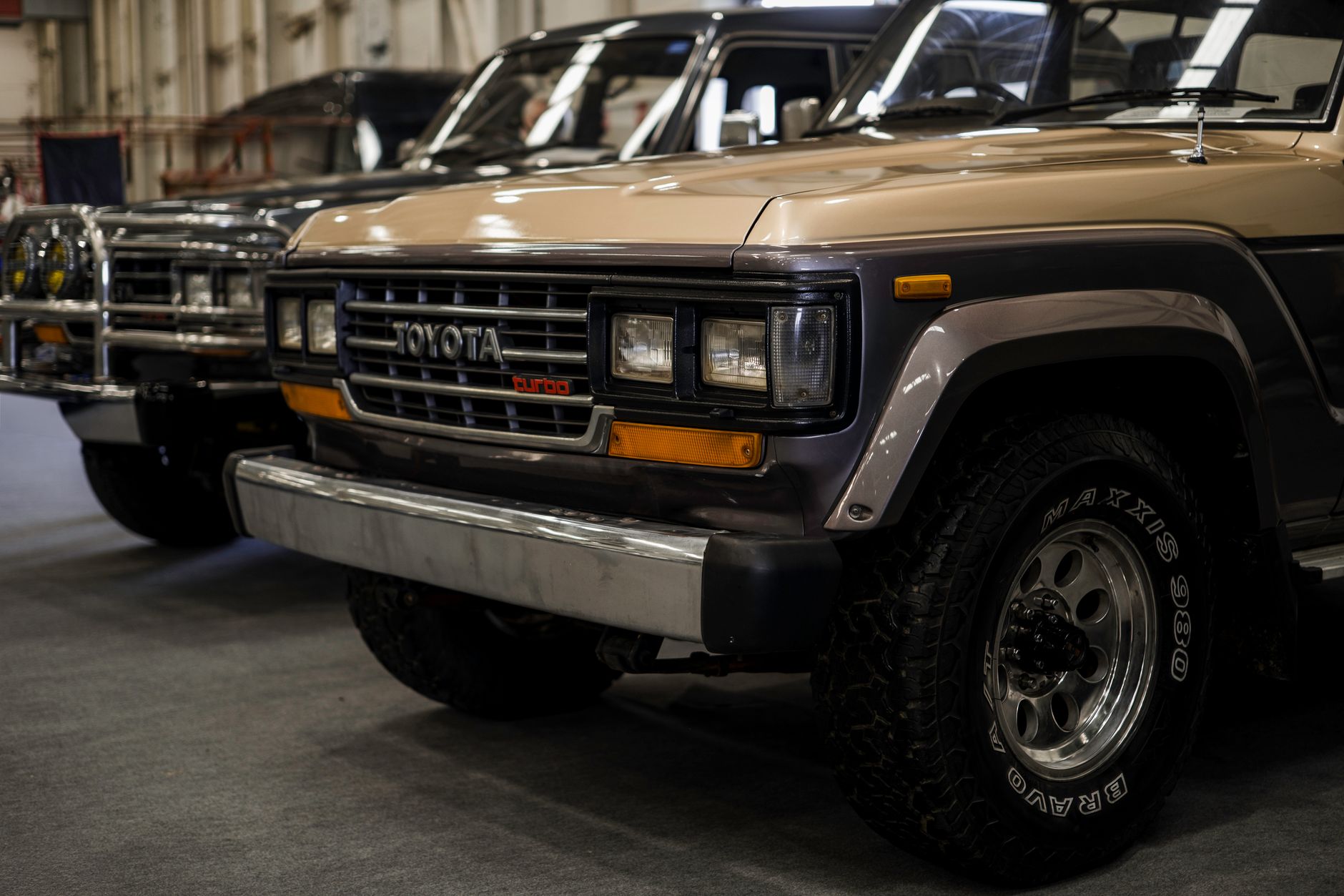 Close-up of a classic Toyota Land Cruiser parked indoors, showcasing its vintage design and sturdy build.