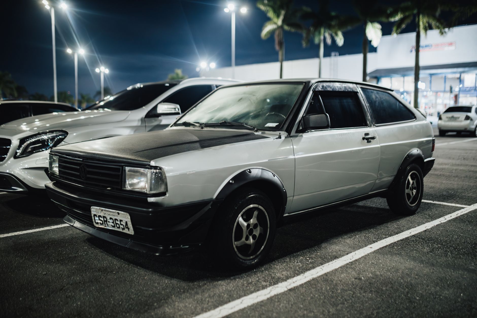 Classic retro car parked in a city lot at night, showcasing vintage charm.