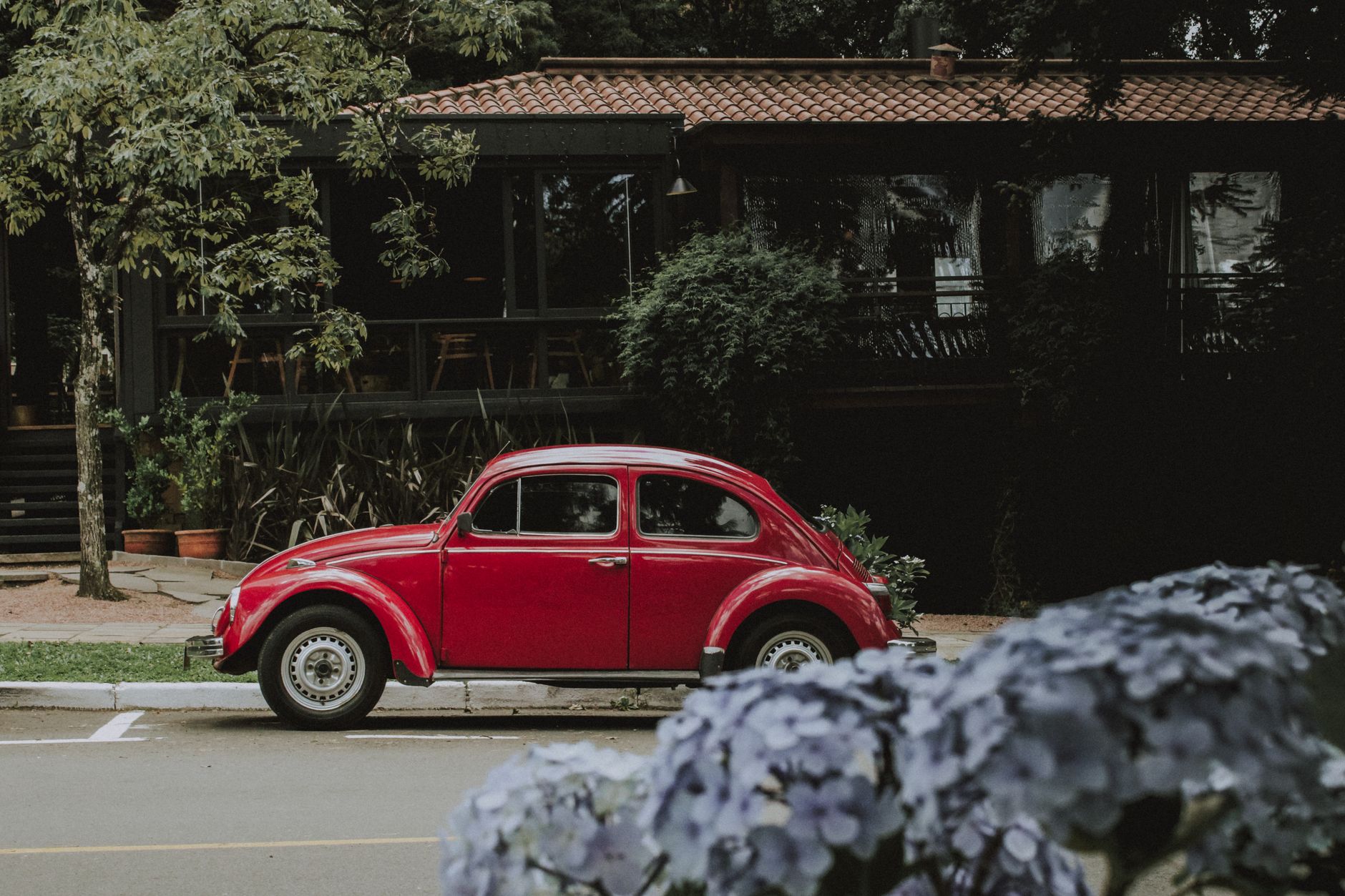 A classic red Volkswagen Beetle parked in scenic Gramado, Brazil, showcasing vintage automotive charm.