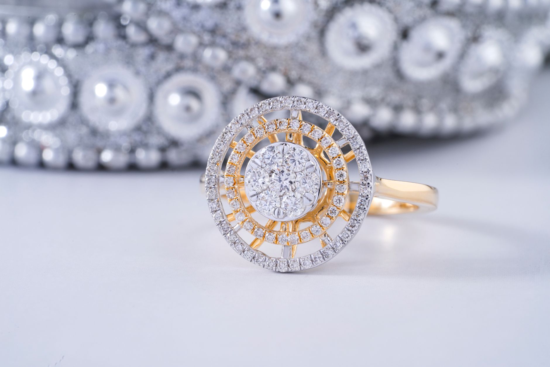 Close-up of an elegant diamond ring with intricate design on a reflective surface.