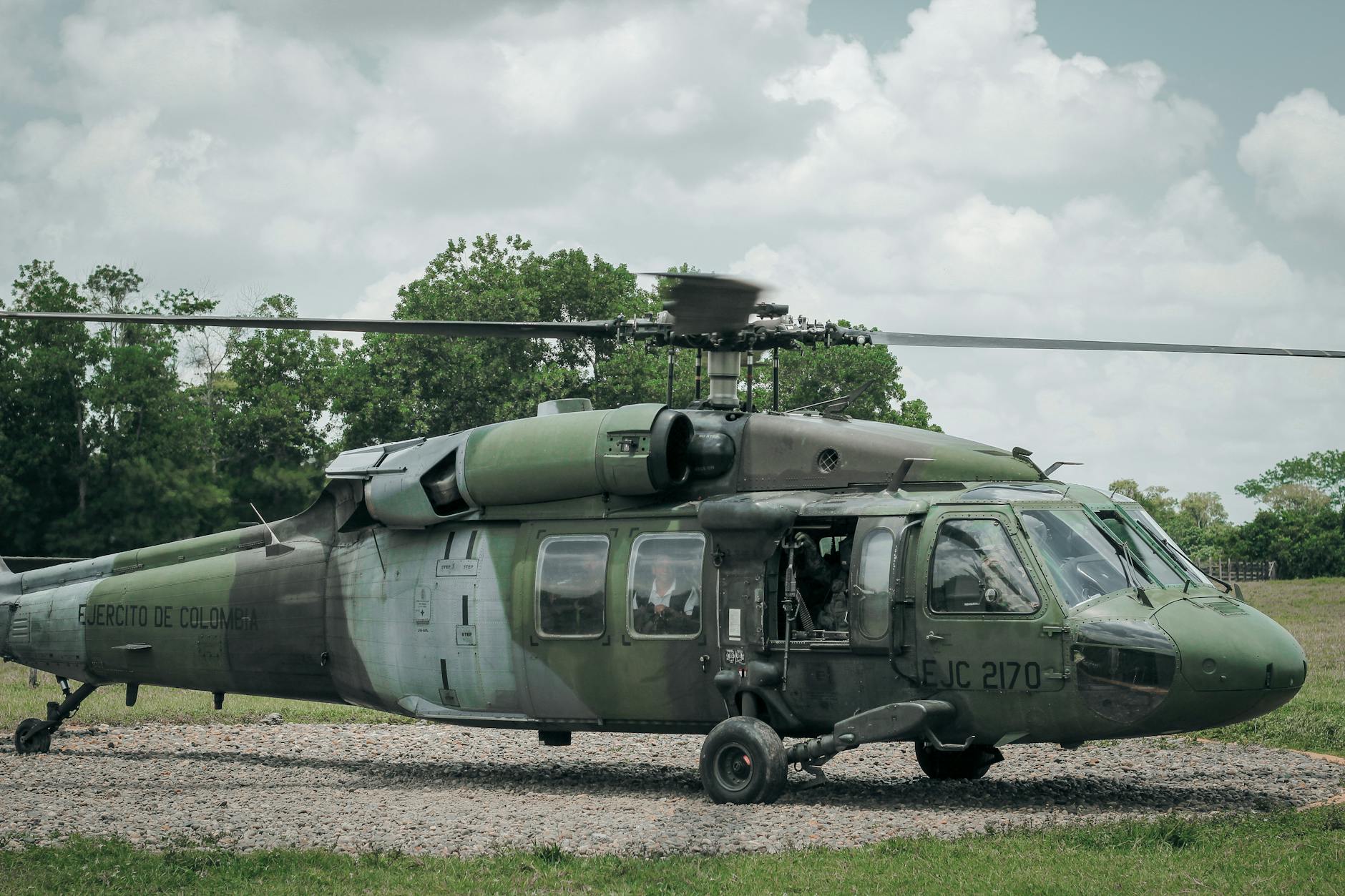 A military helicopter stationed outdoors in a Colombian landscape.