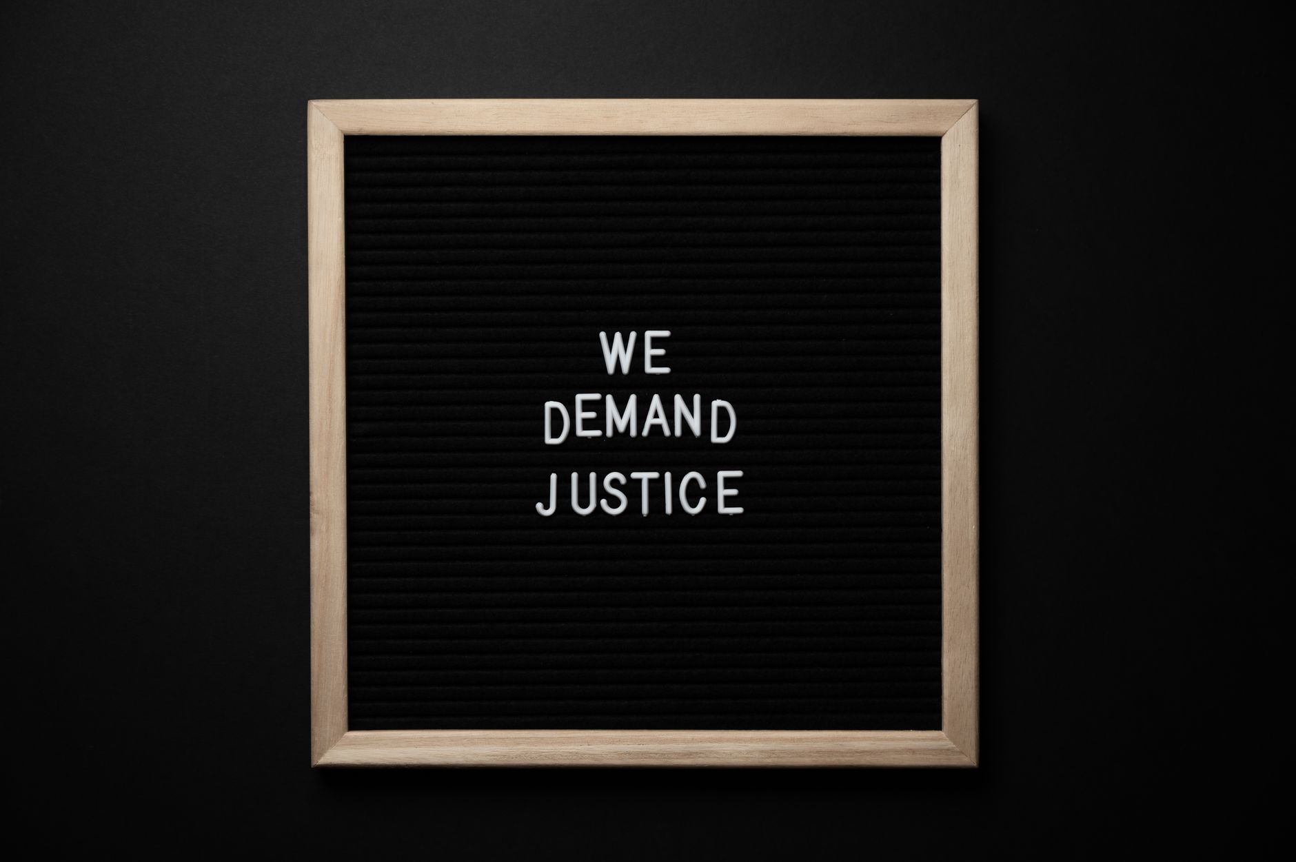 From above wooden frame with we demand justice text placed on black table
