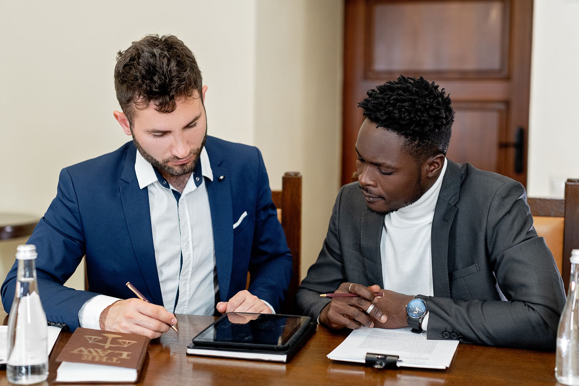 Two businessmen collaborating over documents and a digital tablet during a meeting.