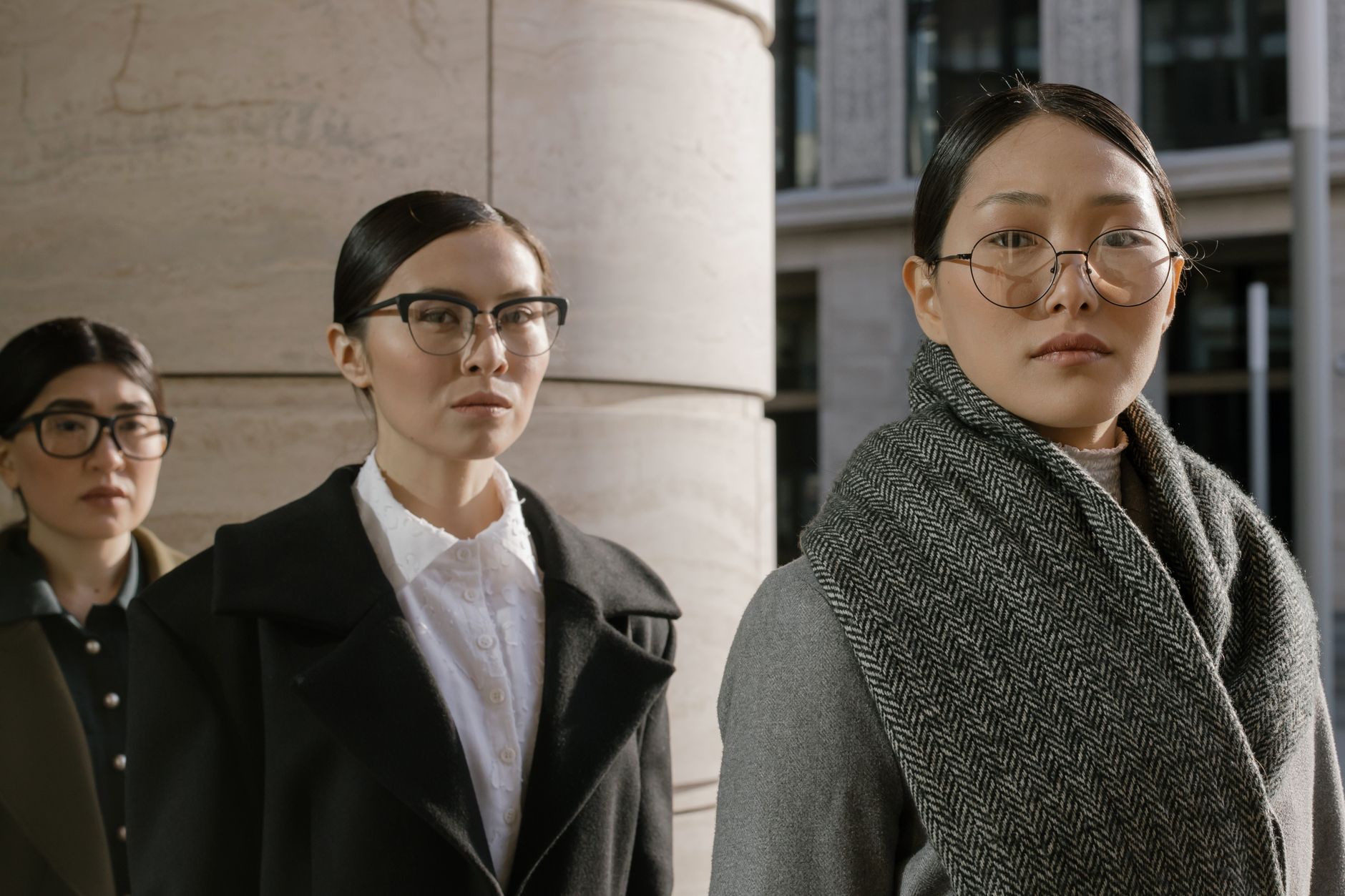 Three stylish women in business attire outdoors, exuding confidence and elegance.