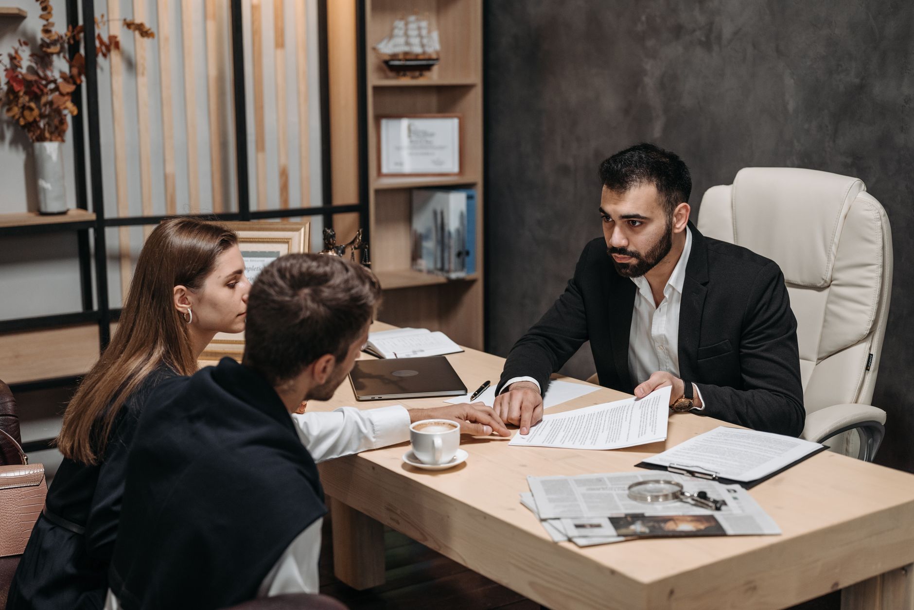 Lawyer discussing legal documents with clients at office desk.