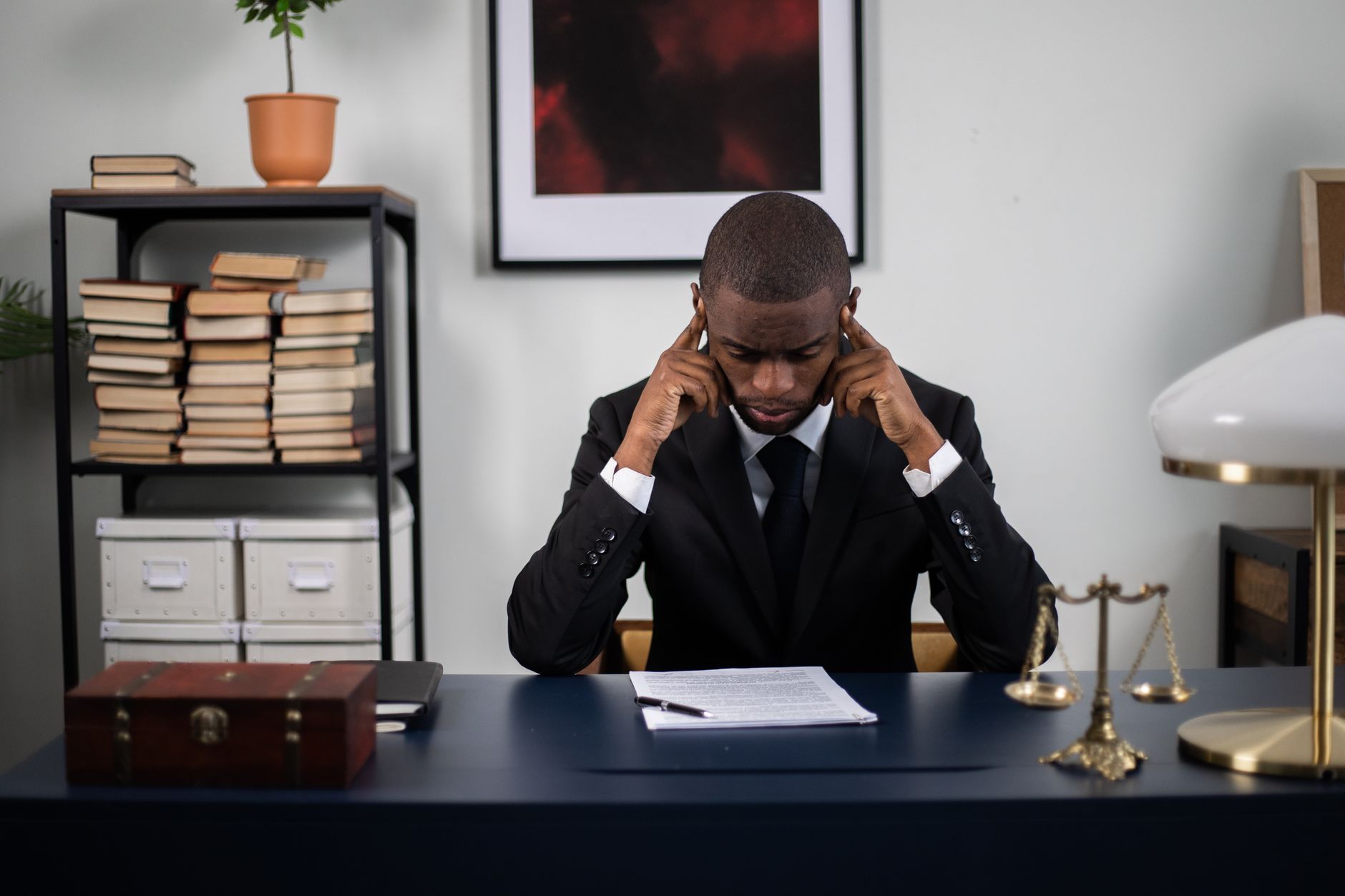 Businessman in suit reading documents at office desk, appearing stressed or thoughtful.