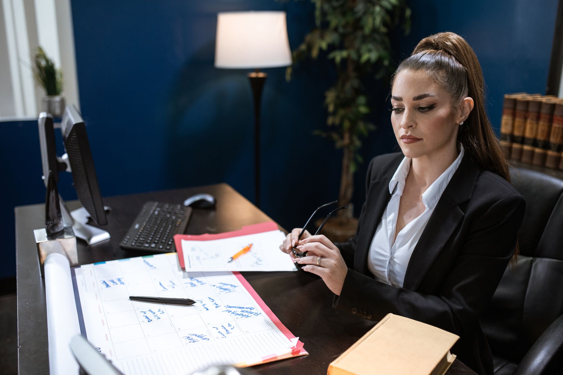 Professional woman in a black blazer working at a desk in a modern office.