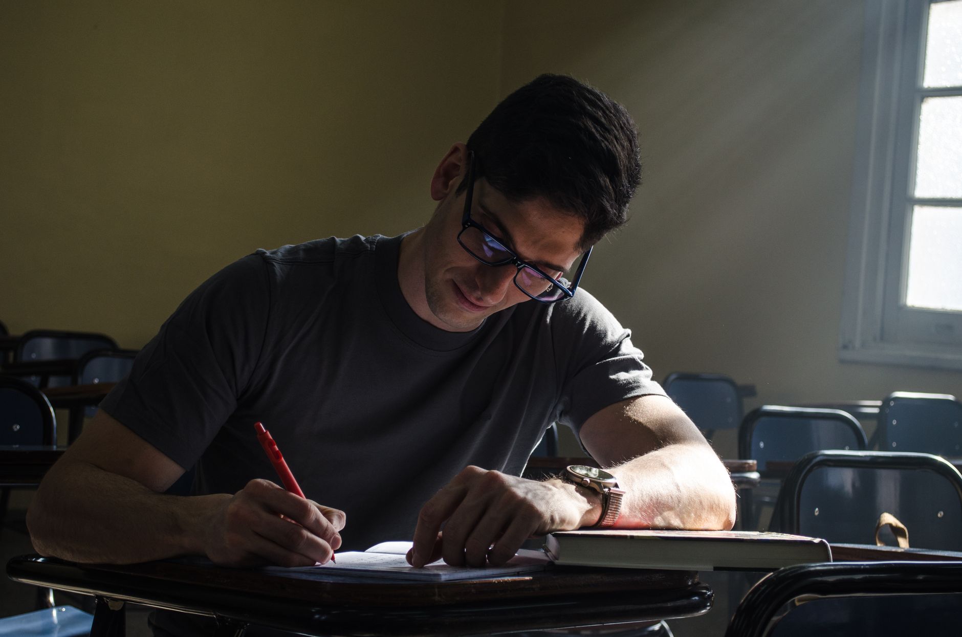 Young man studying in a sunlit classroom in Buenos Aires, Argentina, emphasizing focus and concentration.
